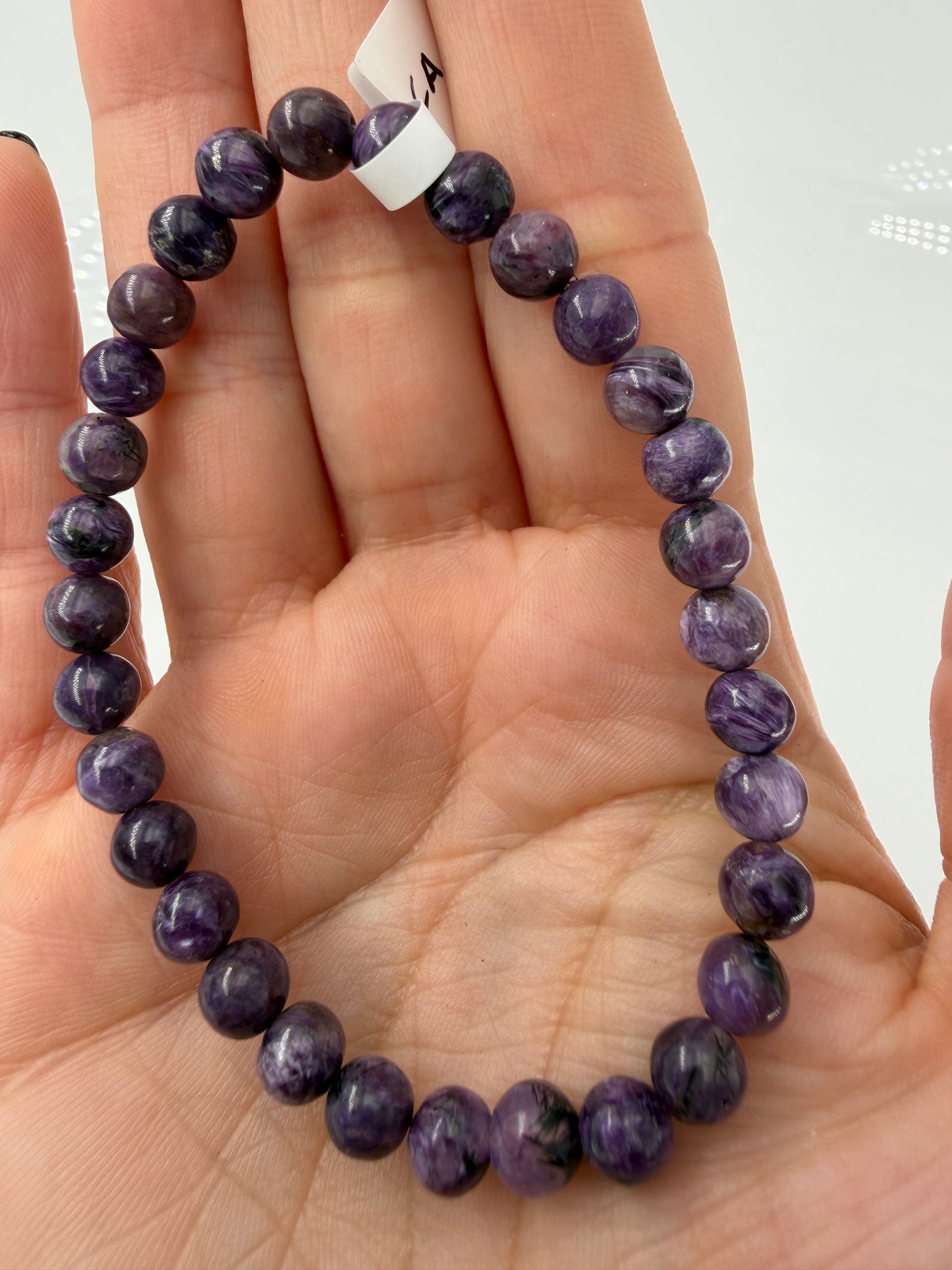 Ein hochwertiges Armband aus tiefvioletten Charoit-Perlen, die eine faszinierende, wirbelförmige Maserung und einen sanften Perlmuttglanz aufweisen.