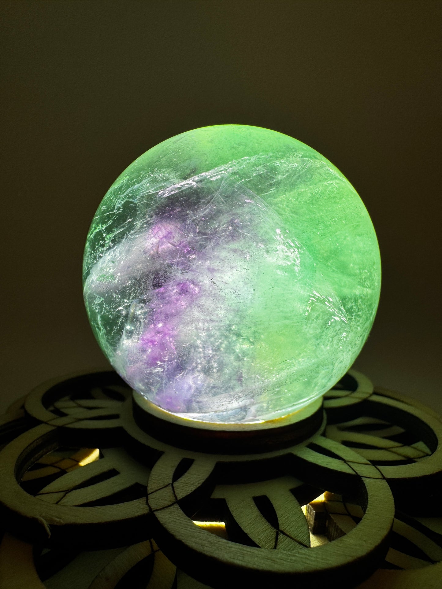 Fluorit-Kugel mit natürlichem Farbverlauf von Smaragdgrün zu Lavendel-Rosa auf einem Leuchtständer.