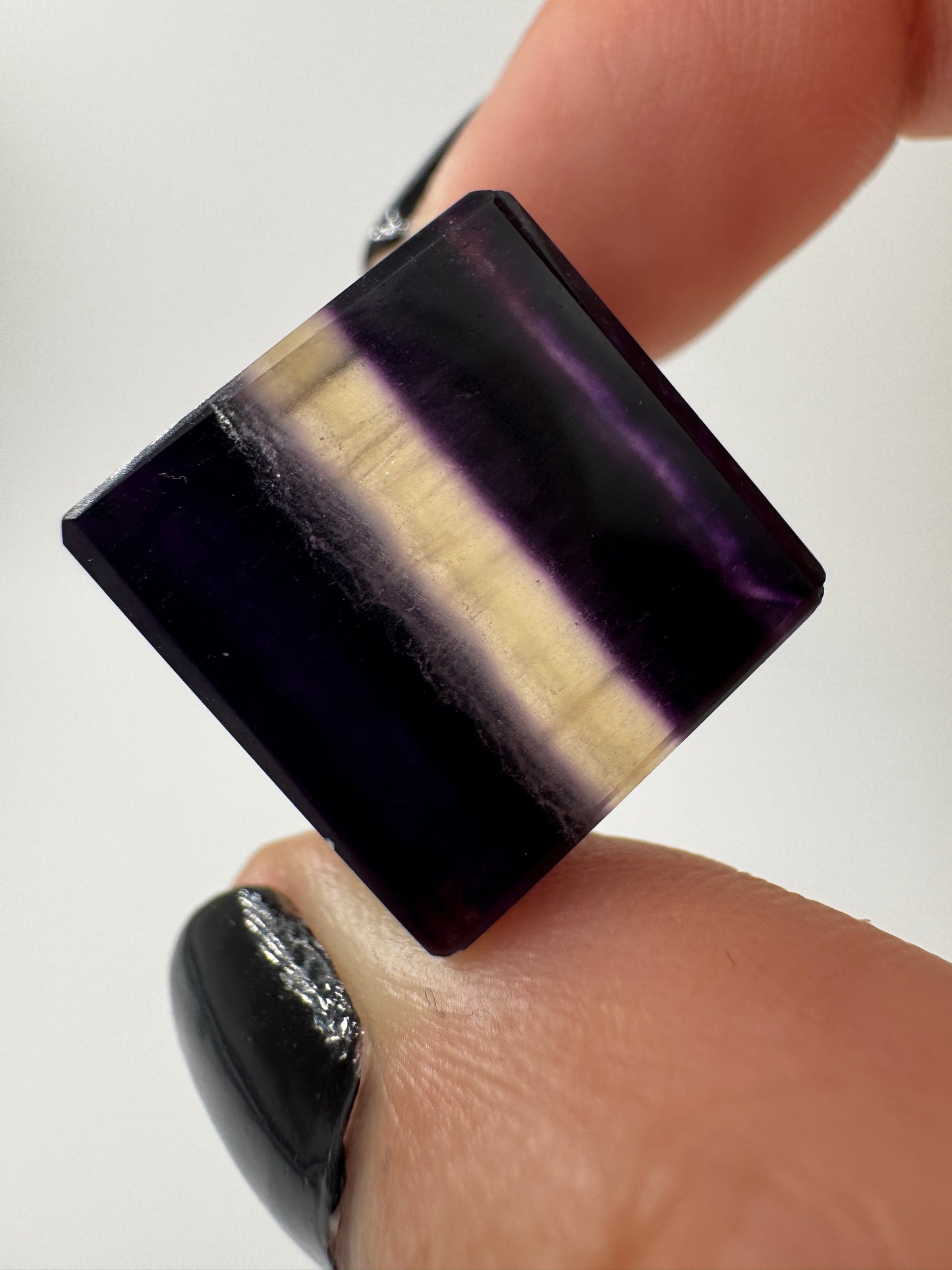 Ein transparenter Fluorit-Würfel mit deutlich sichtbaren violetten Farbbändern.