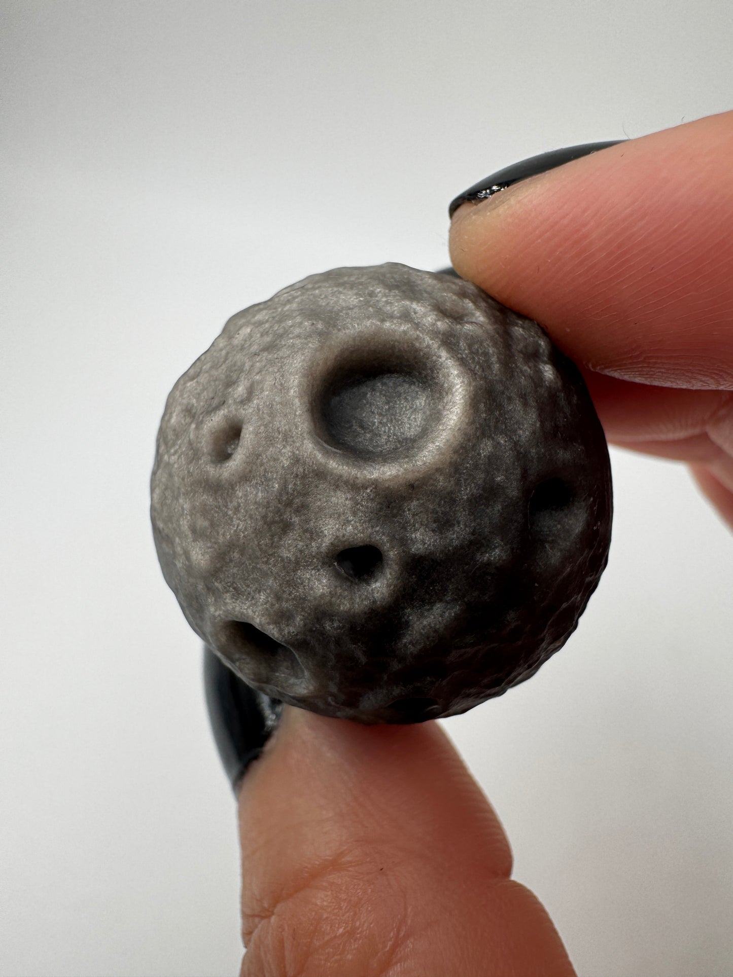 Silber-Obsidian-Mond mit haptischen Kratern und silbrigem Chatoyance-Effekt.