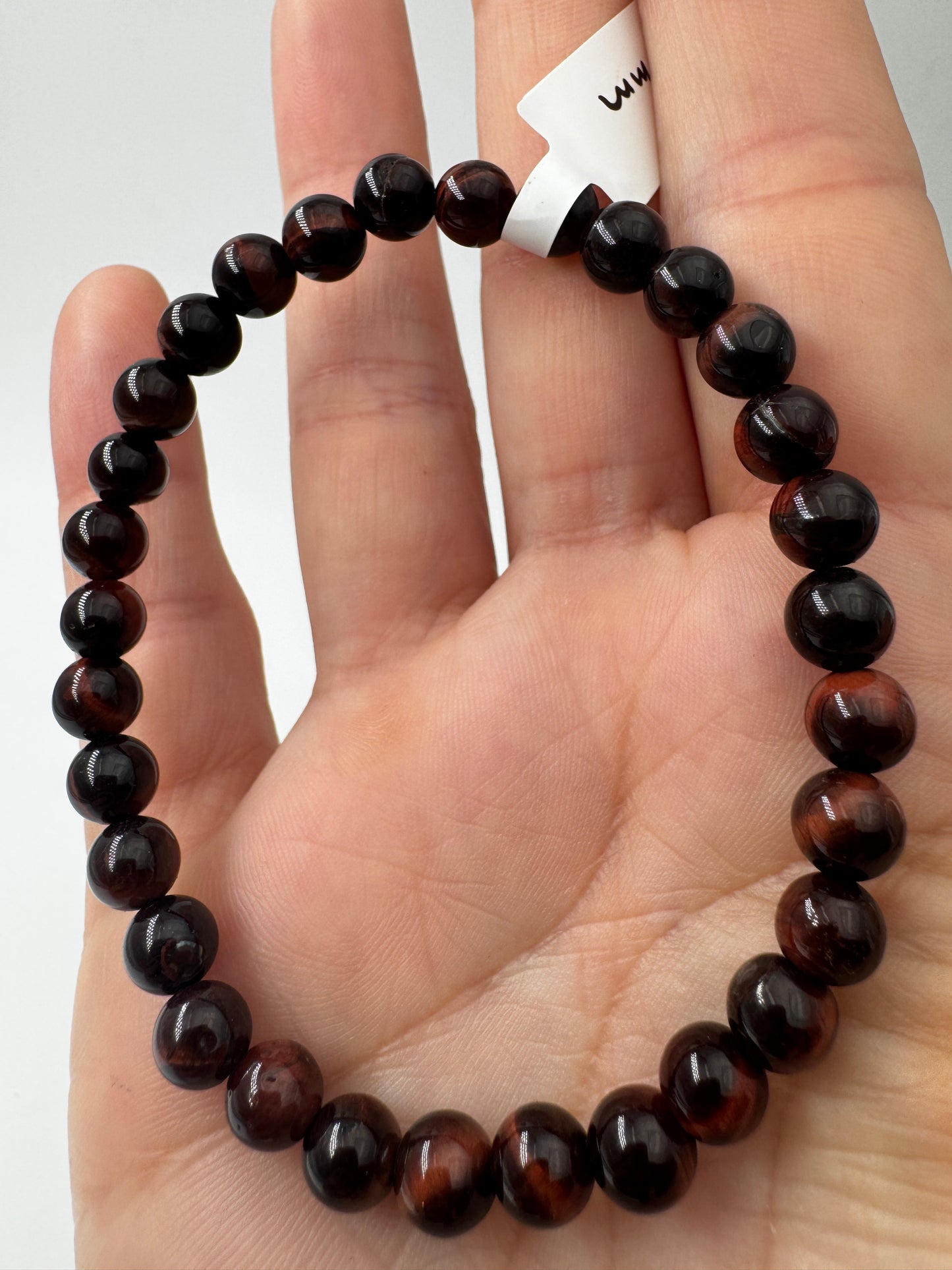 Nahaufnahme eines Kugelarmbands aus rotem Tigerauge mit glänzend polierten Perlen in tiefen Rot- und Brauntönen.