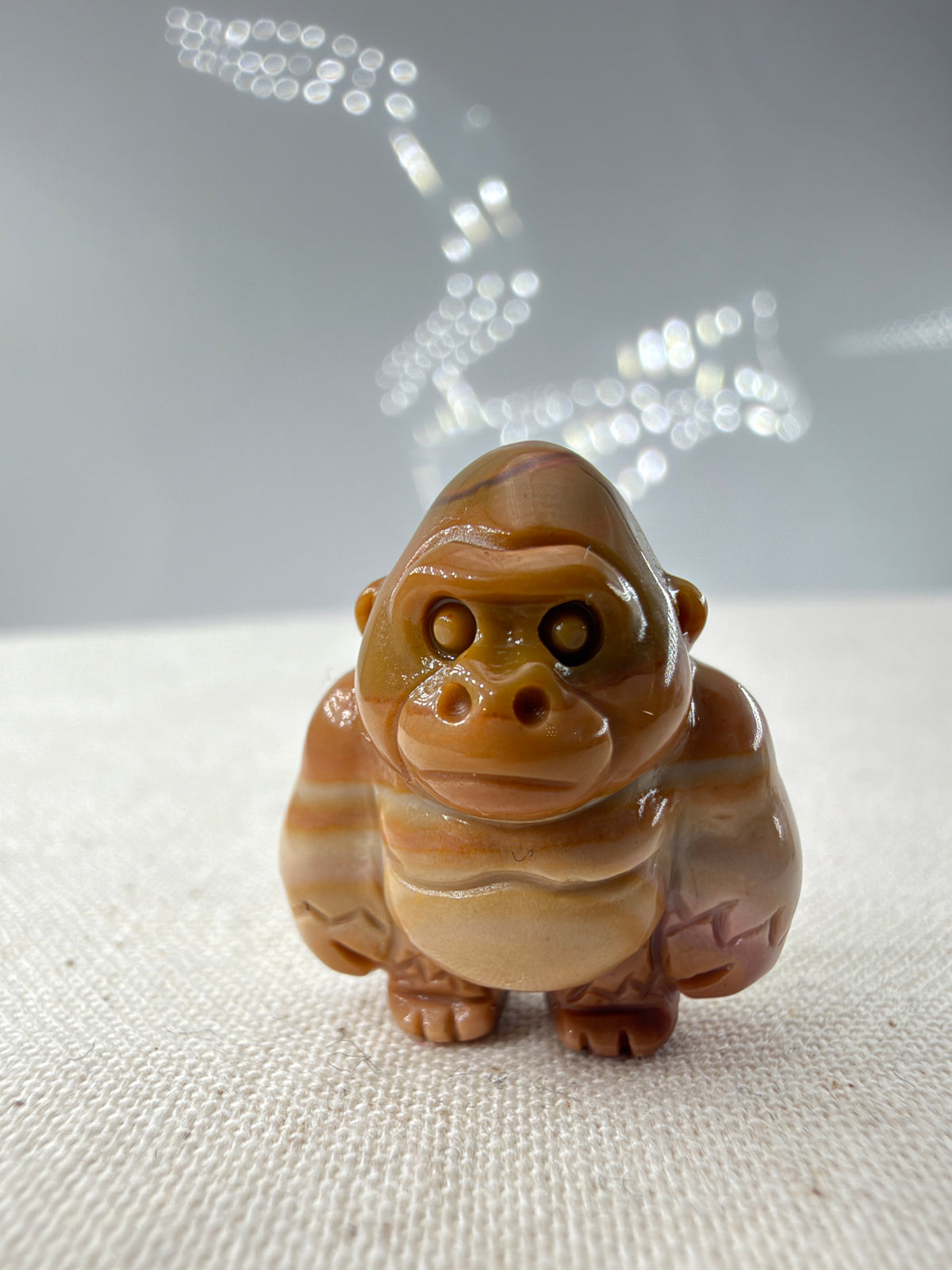 polierte Gorilla-Figur aus Alashan-Achat,  in Braun und Creme, auf hellem Untergrund