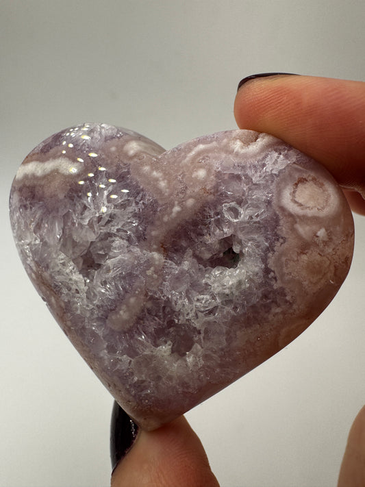 Herzförmiges Carving aus tiefviolettem Amethyst und Blumenachat mit dendritischen Einschlüssen.