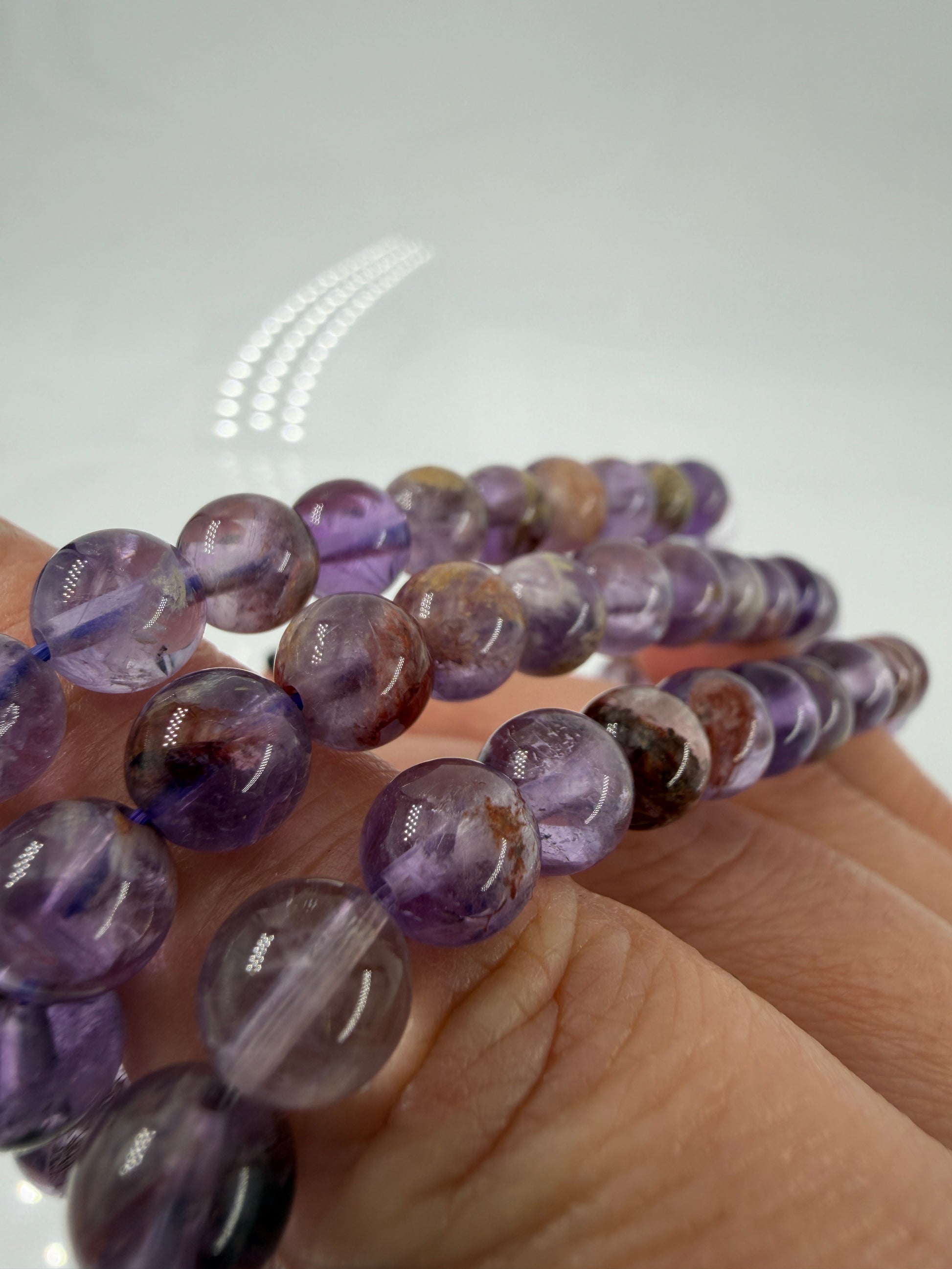 Detailansicht einer Amethyst-Kugel mit mineralischen Einschlüssen (Garten-Effekt) und violetten Phantombildungen.