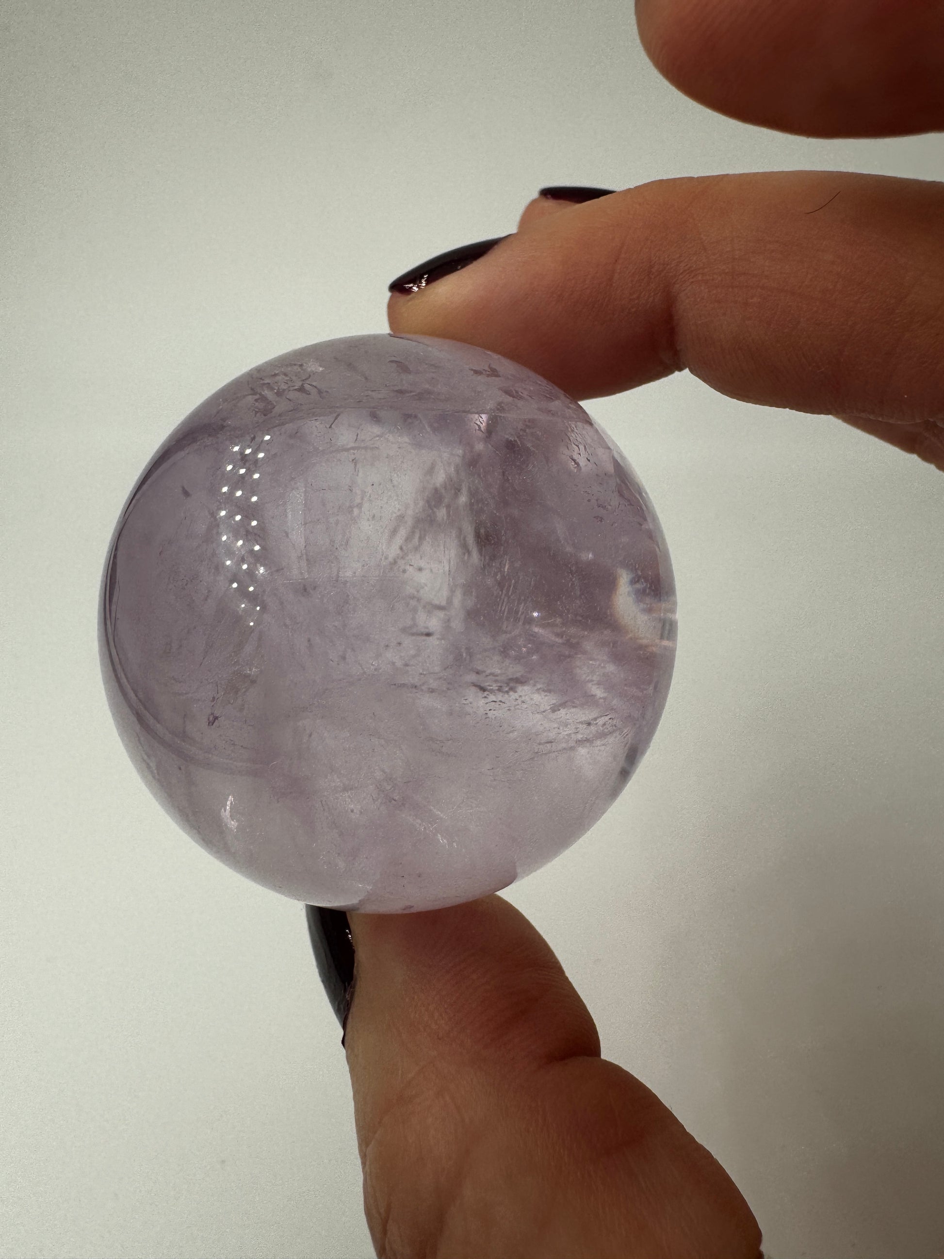Handpolierte Amethyst-Kugel AK32 mit zartem Violett und feinen Zonarstrukturen.