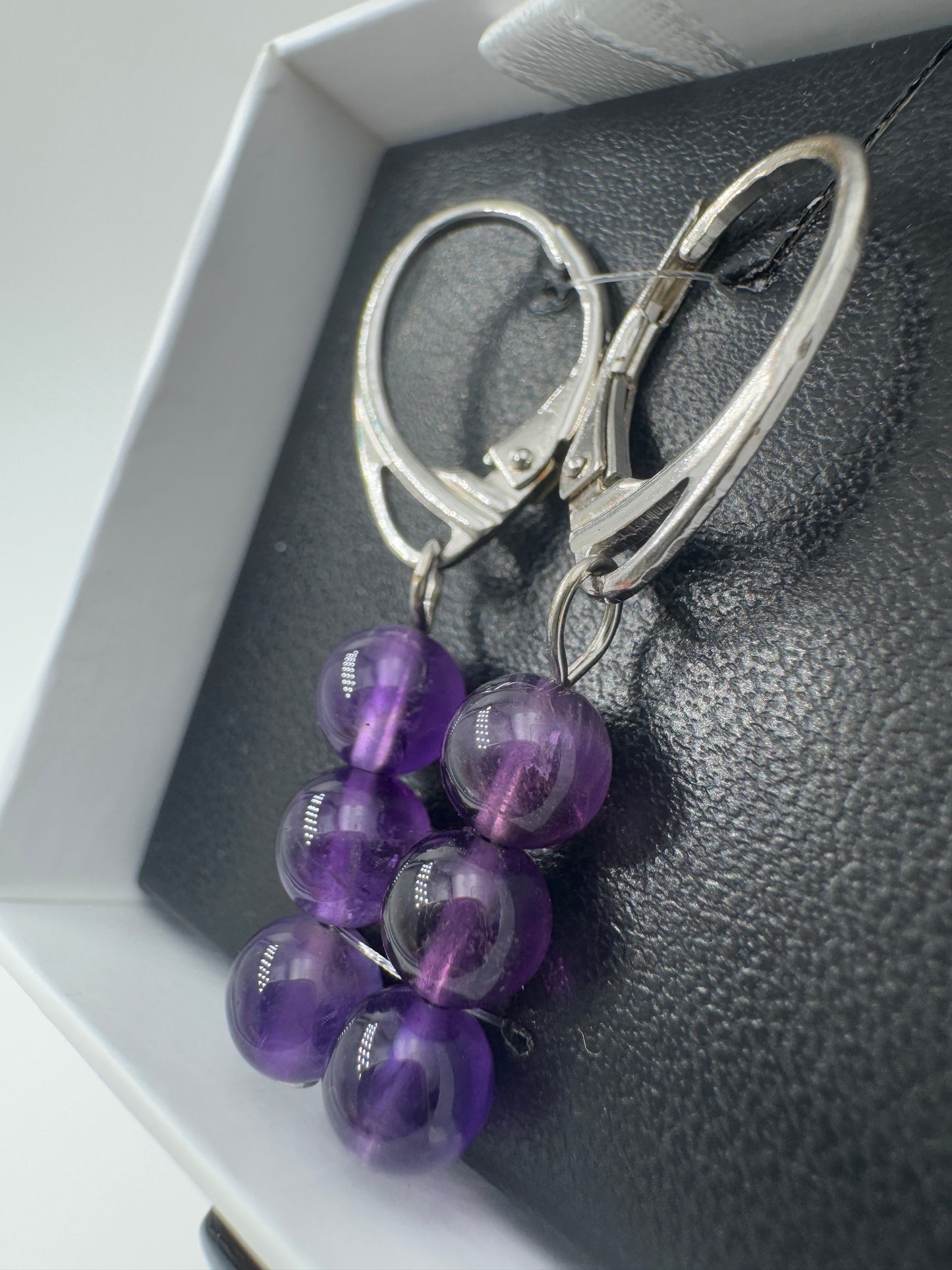 Ein Paar hochwertige Ohrhänger mit intensiv violetten Amethyst-Kugeln, deren transparente Struktur das Licht in feinen Facetten bricht.