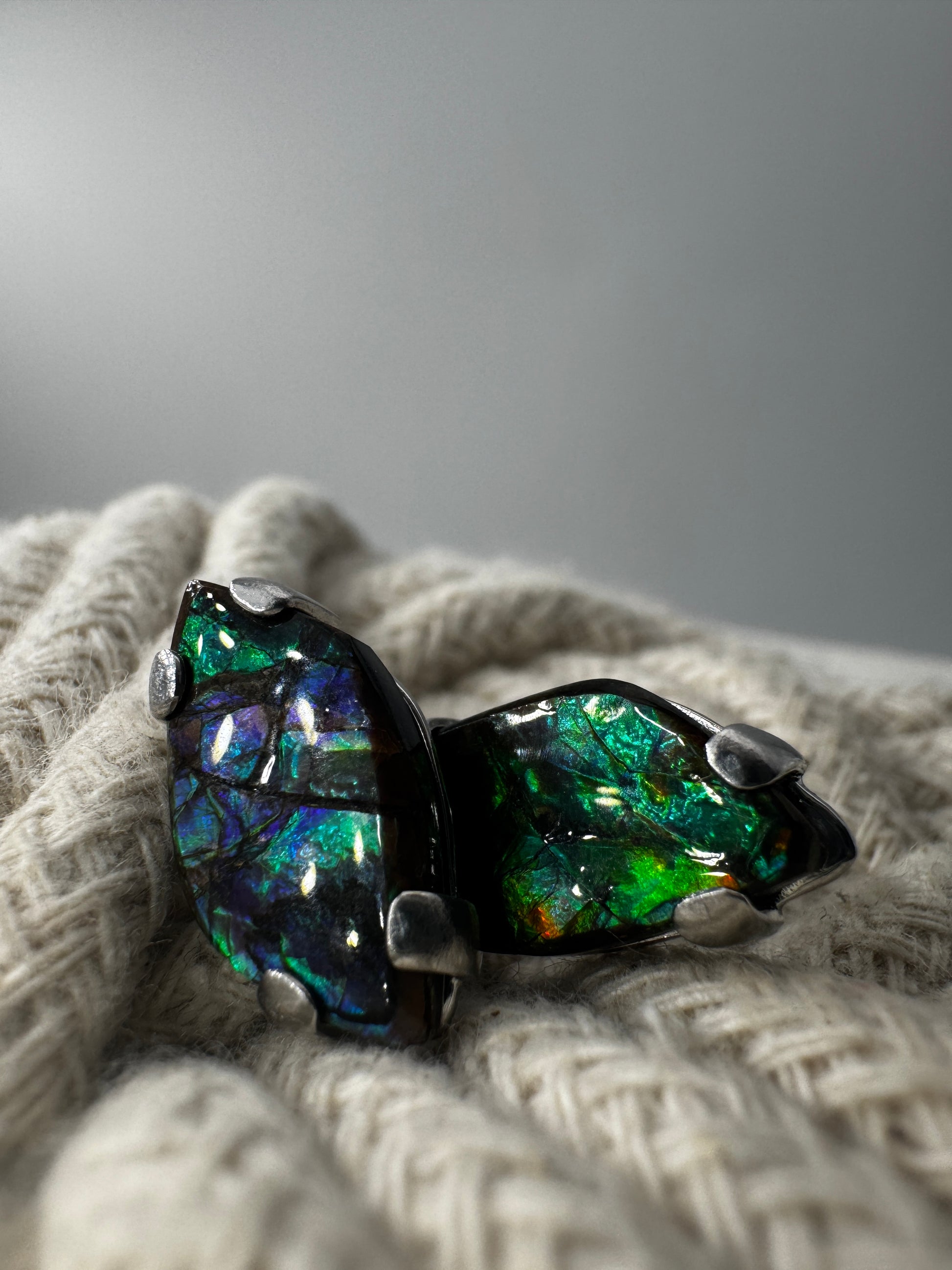 Ohrstecker aus Ammolith in Silberfassung, 1,8 × 1 cm, mit irisierendem Farbenspiel in  Grün und Blau.
