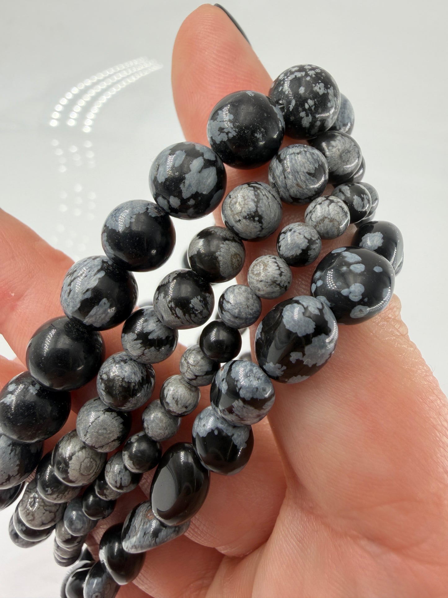 Kugelarmband aus Schneeflocken-Obsidian mit markanten weißen Cristobalit-Einschlüssen auf schwarzem Grund.