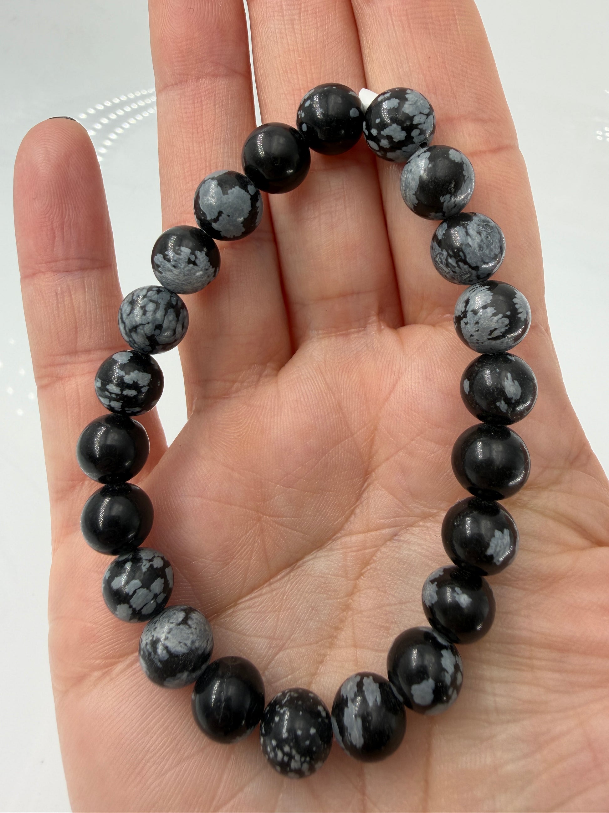 Kugelarmband aus Schneeflocken-Obsidian mit markanten weißen Cristobalit-Einschlüssen auf schwarzem Grund.