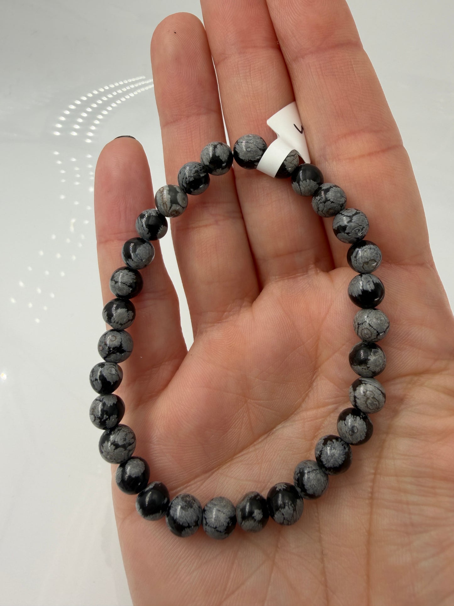 Kugelarmband aus Schneeflocken-Obsidian mit markanten weißen Cristobalit-Einschlüssen auf schwarzem Grund.