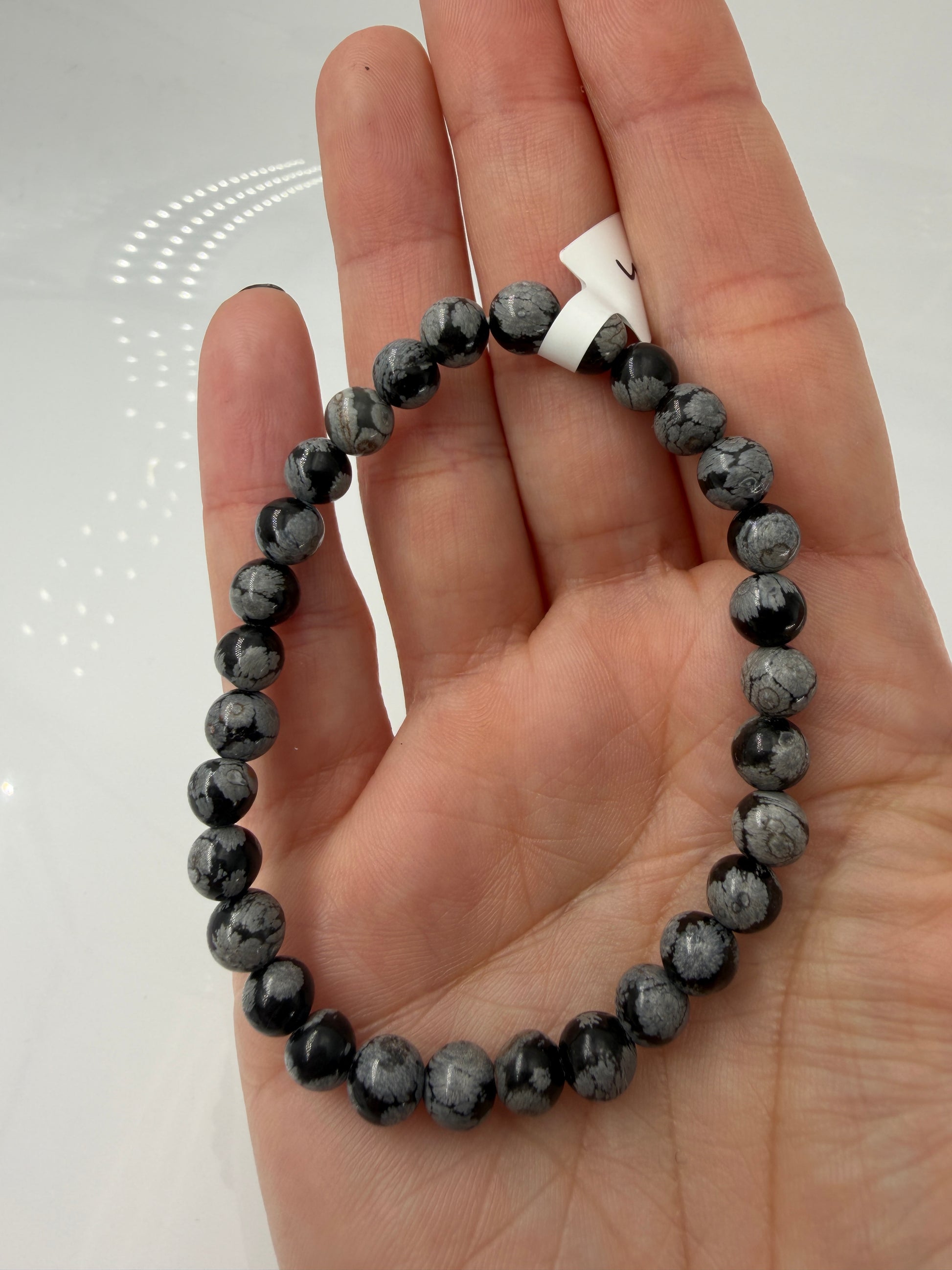 Kugelarmband aus Schneeflocken-Obsidian mit markanten weißen Cristobalit-Einschlüssen auf schwarzem Grund.