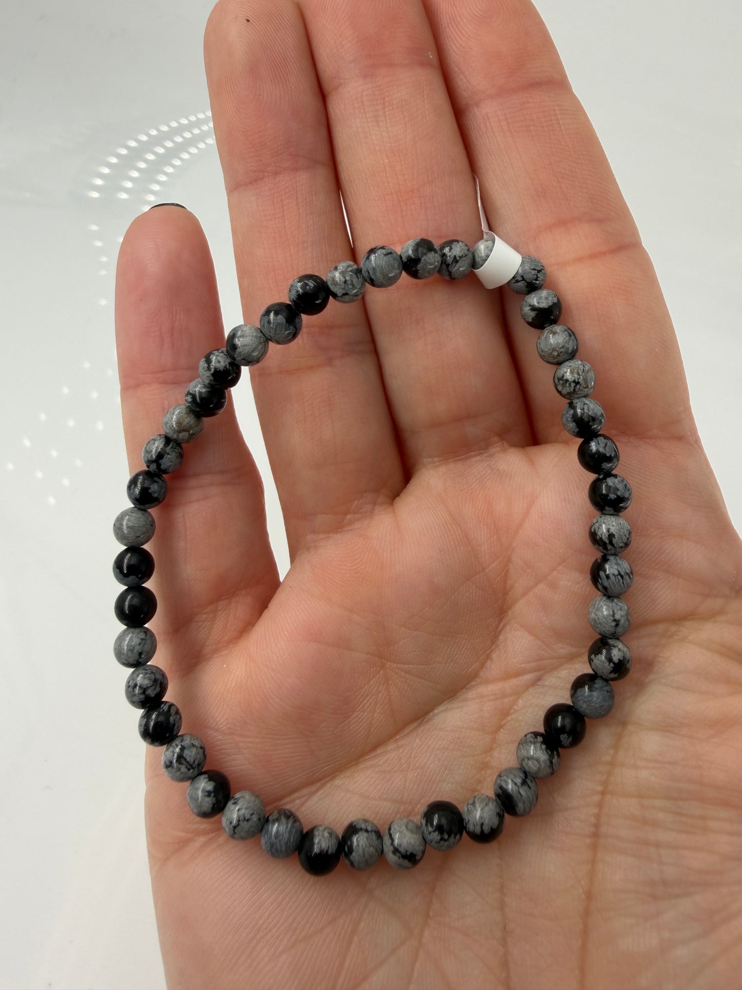 Kugelarmband aus Schneeflocken-Obsidian mit markanten weißen Cristobalit-Einschlüssen auf schwarzem Grund.