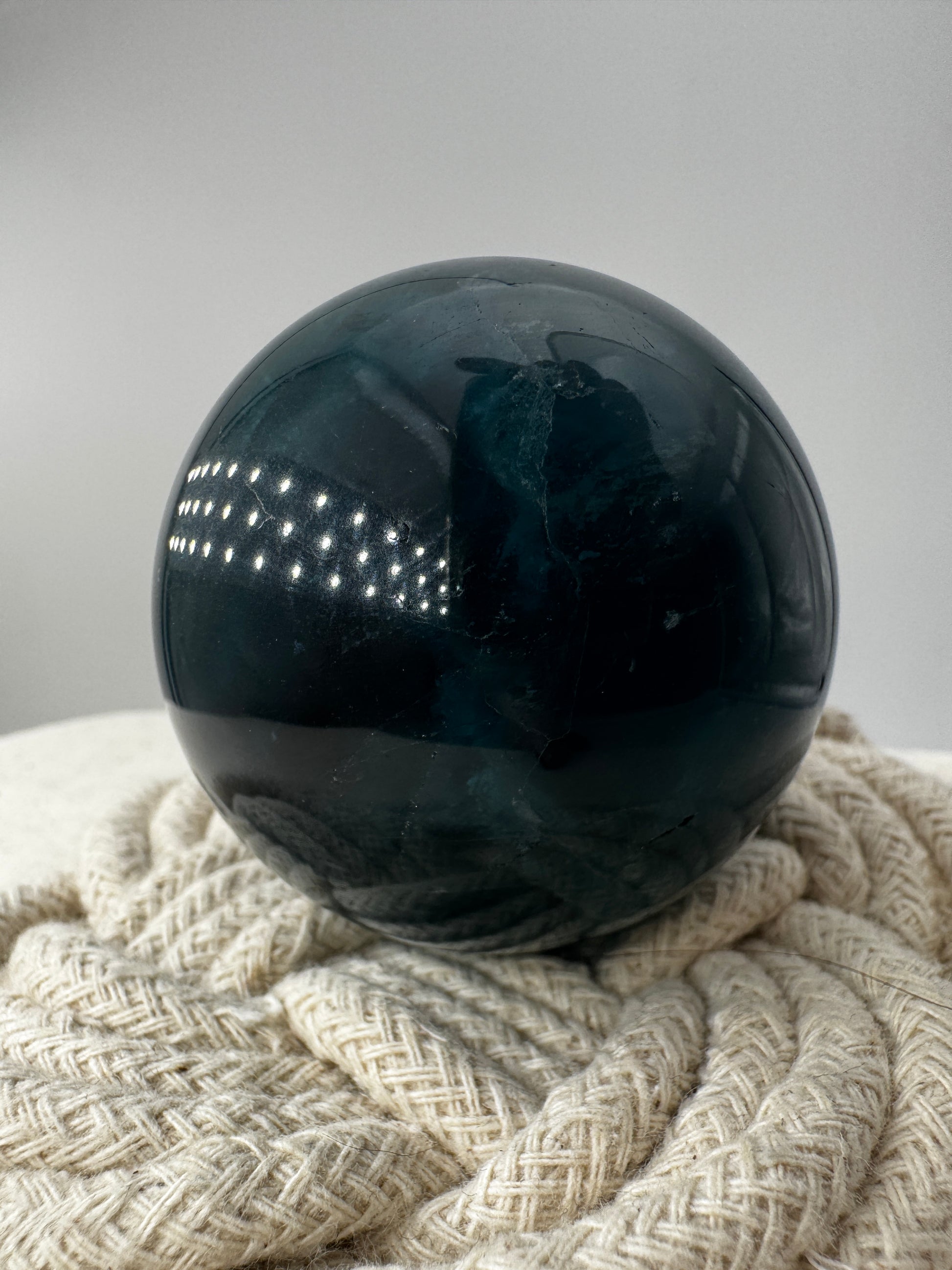 Eine tiefblaue, polierte Fluorit-Kugel mit inneren Wachstumsstrukturen und einem minimalen, authentischen Oberflächenmerkmal.