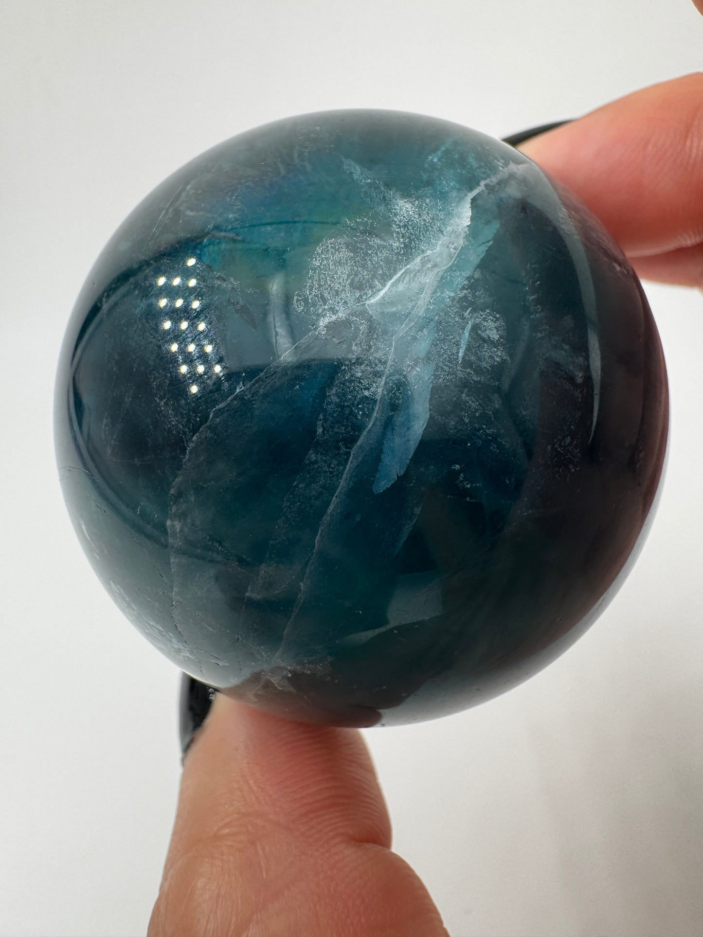 Eine tiefblaue, polierte Fluorit-Kugel mit inneren Wachstumsstrukturen und einem minimalen, authentischen Oberflächenmerkmal.