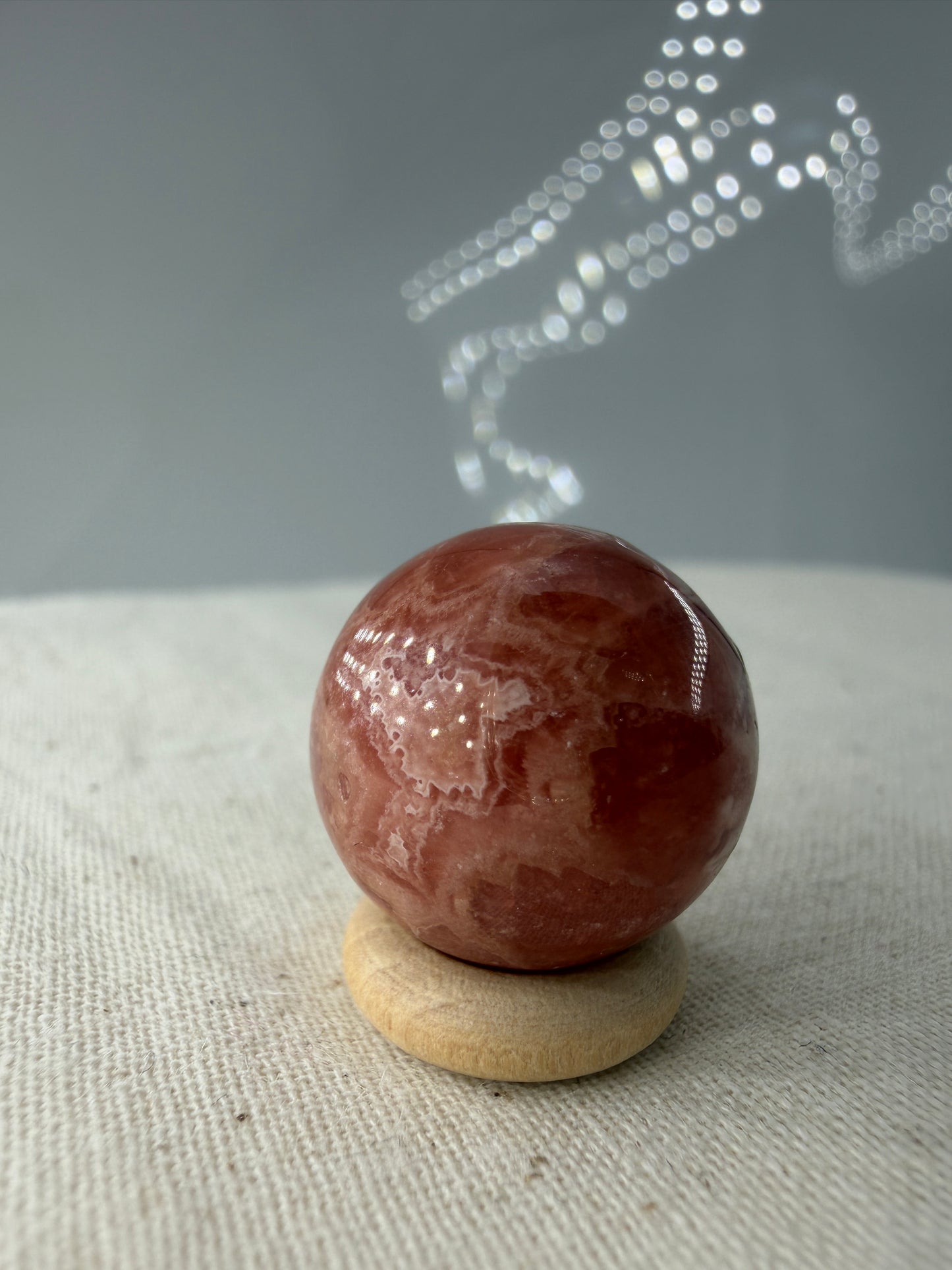 Polierte Kugel aus Rhodochrosit mit leuchtend rosa konzentrischen Bändern, Durchmesser 1,7 cm, B-Ware mit kleinen Macken.