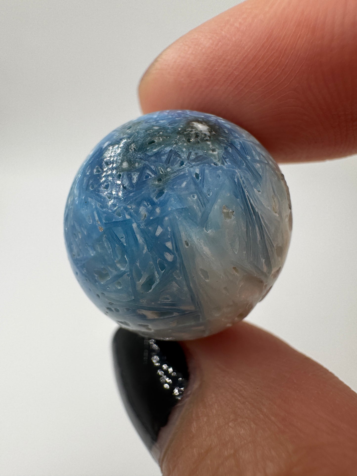 Eine perfekt sphärische Kugel aus Blue Ice Glacierite, deren glänzende Oberfläche das Licht reflektiert und den Blick auf die einmalige Strucktur freigibt.