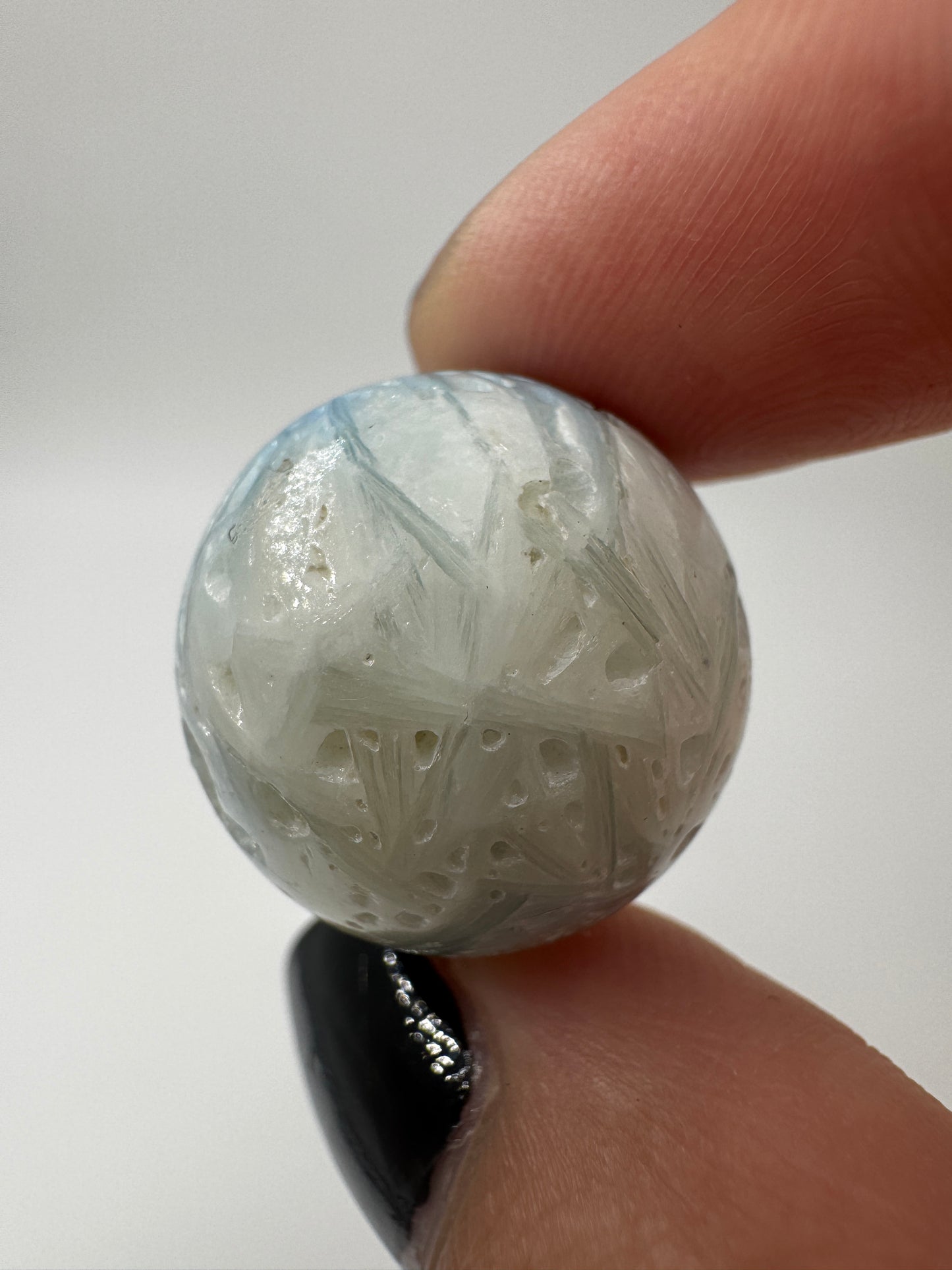 Eine perfekt sphärische Kugel aus Blue Ice Glacierite, deren glänzende Oberfläche das Licht reflektiert und den Blick auf die einmalige Strucktur freigibt.