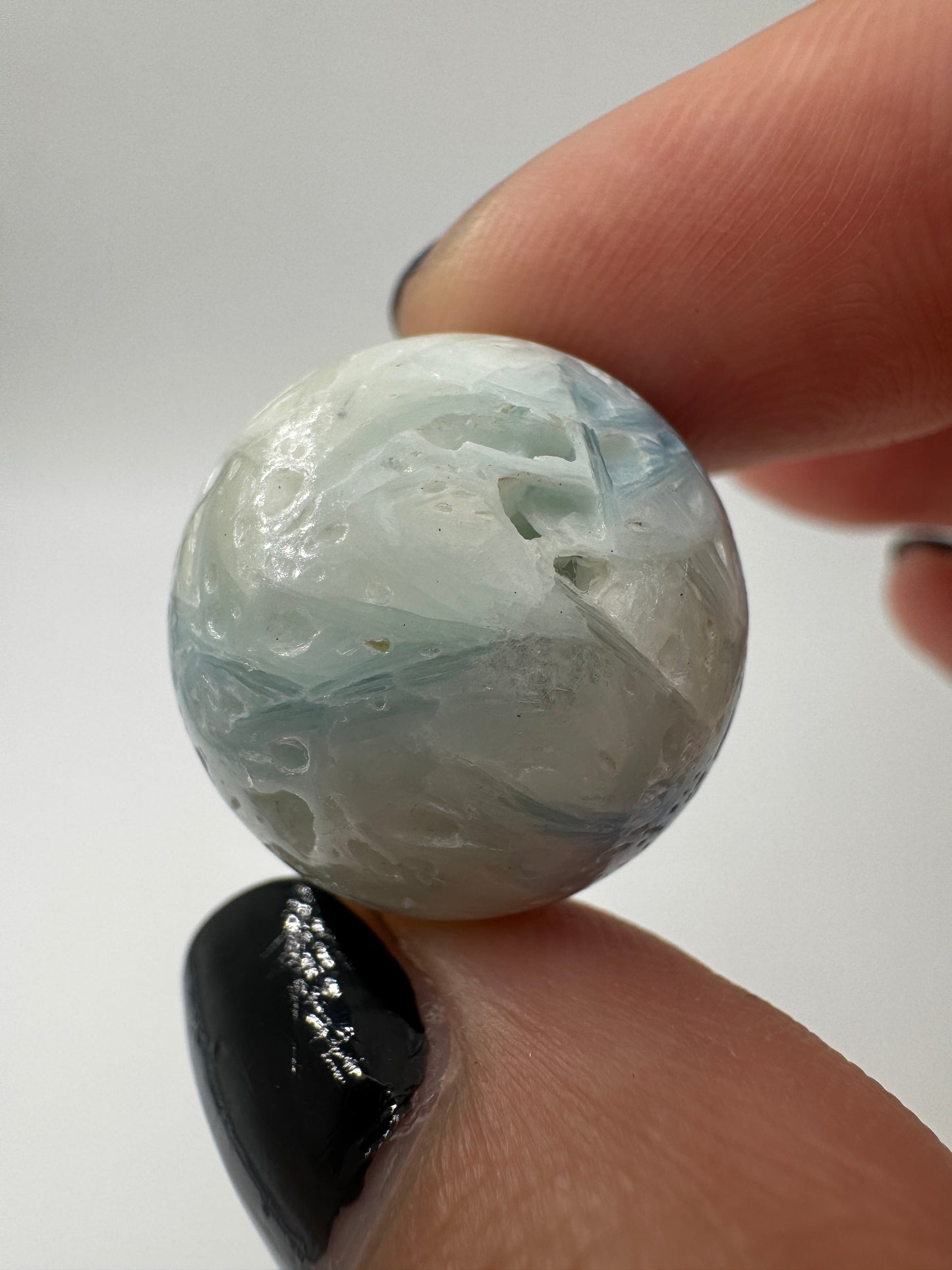 Eine perfekt sphärische Kugel aus Blue Ice Glacierite, deren glänzende Oberfläche das Licht reflektiert und den Blick auf die einmalige Strucktur freigibt.