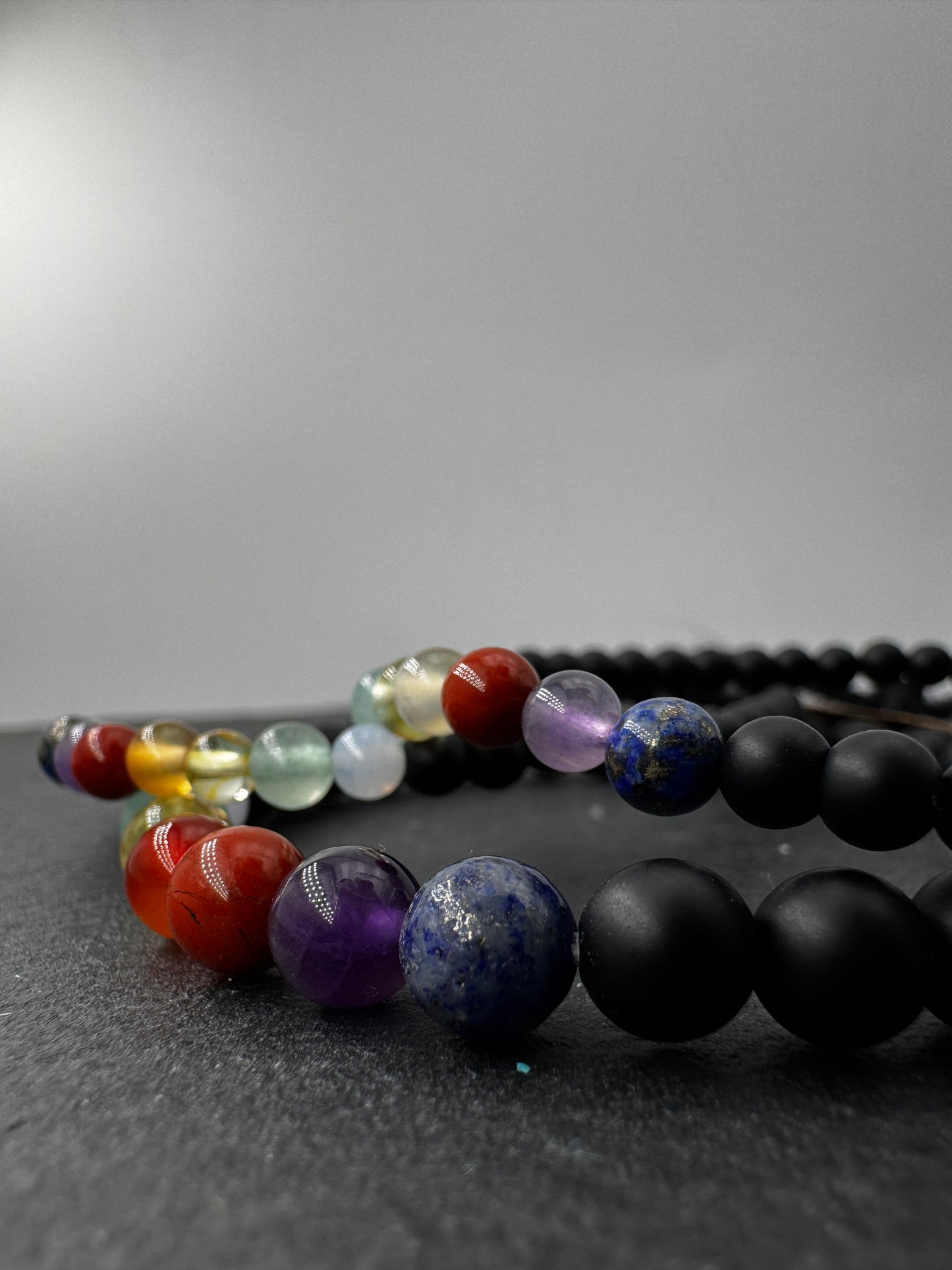 Armband aus mattem schwarzen Onyx mit sieben Chakra-Edelsteinkugeln in Lapislazuli, Amethyst, Jaspis, Karneol, Citrin, Aventurin und Aquamarin, 18 cm Umfang.