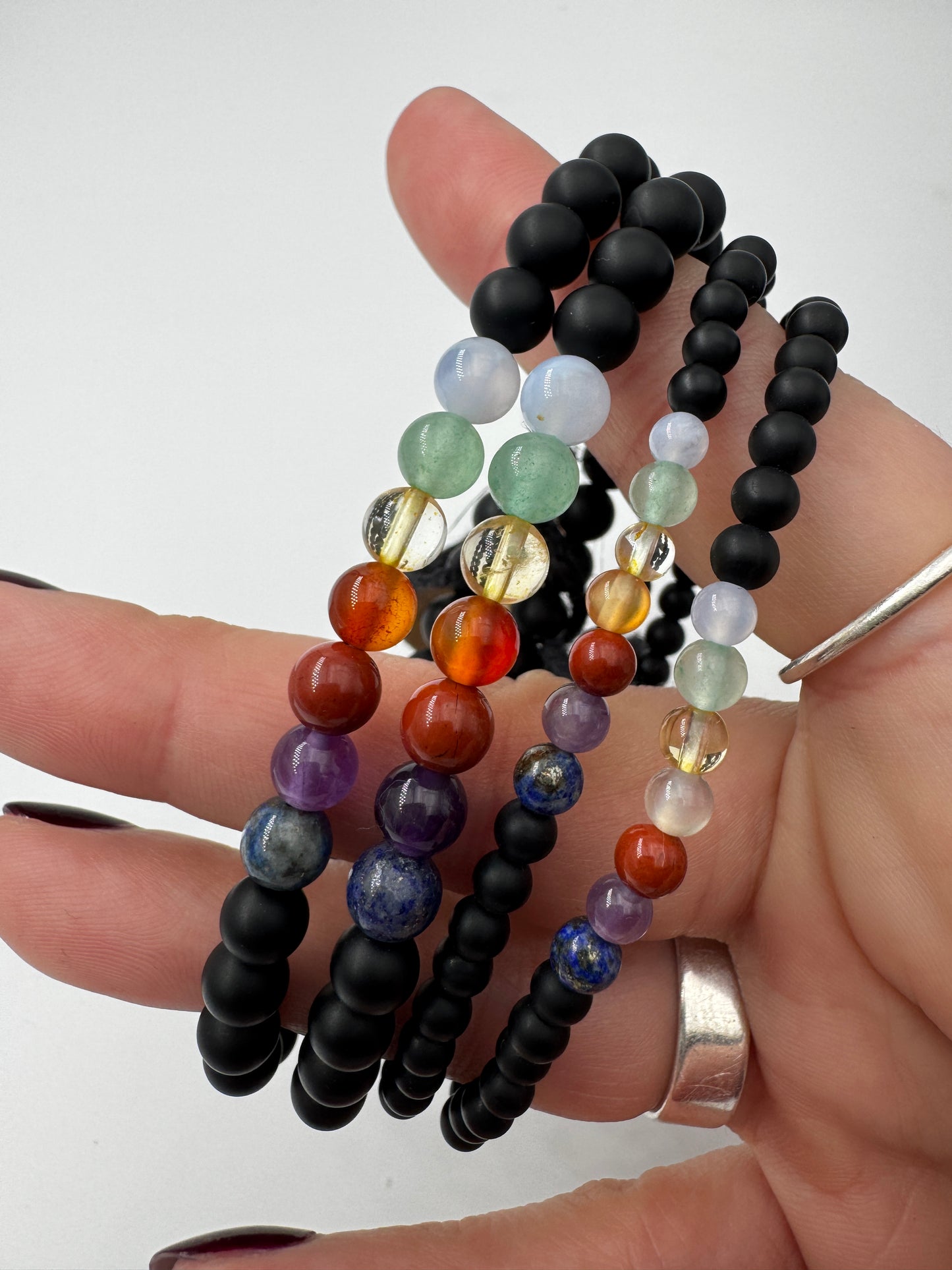 Armband aus mattem schwarzen Onyx mit sieben Chakra-Edelsteinkugeln in Lapislazuli, Amethyst, Jaspis, Karneol, Citrin, Aventurin und Aquamarin, 18 cm Umfang.
