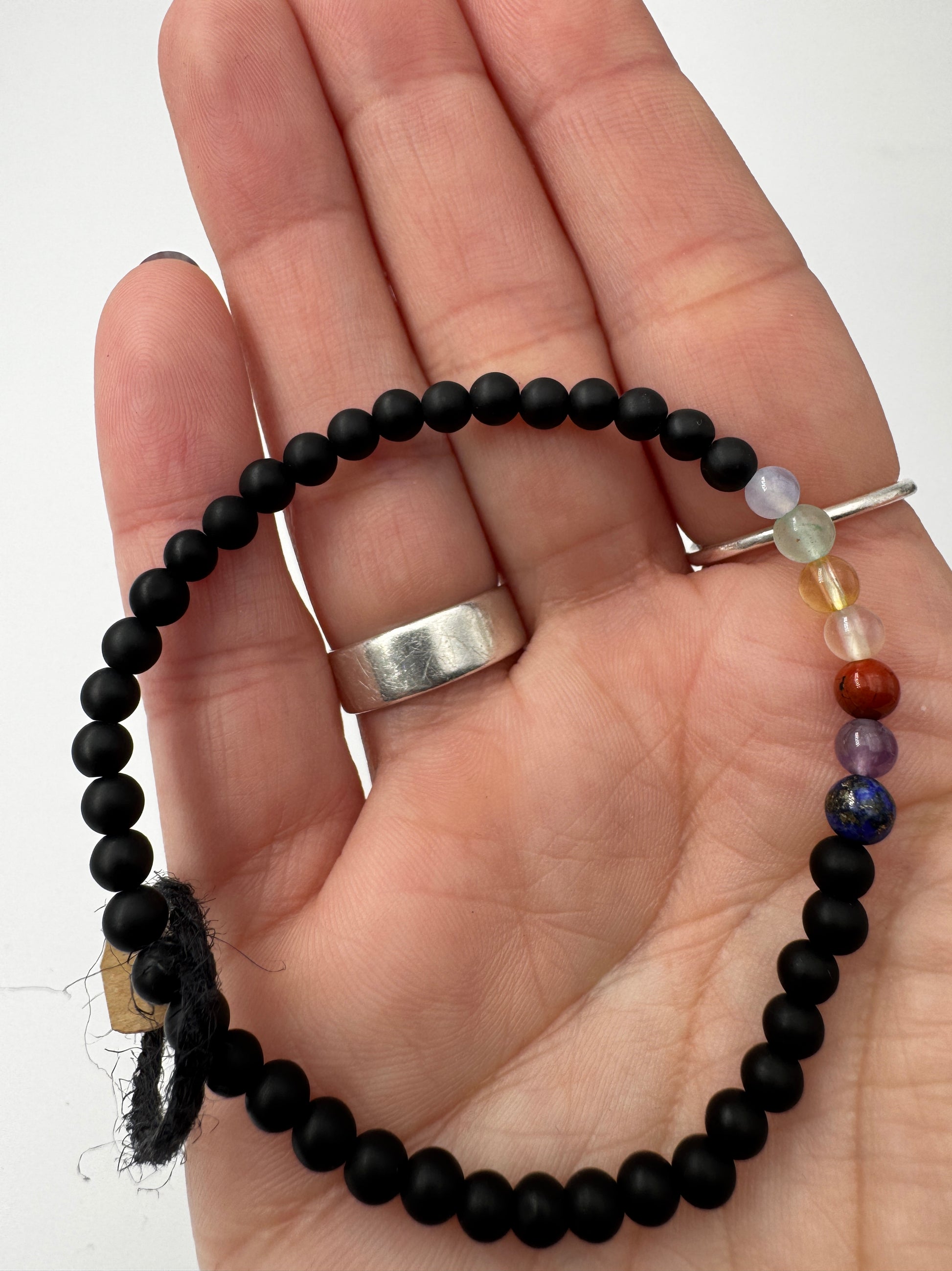 Armband aus mattem schwarzen Onyx mit sieben Chakra-Edelsteinkugeln in Lapislazuli, Amethyst, Jaspis, Karneol, Citrin, Aventurin und Aquamarin, 18 cm Umfang.