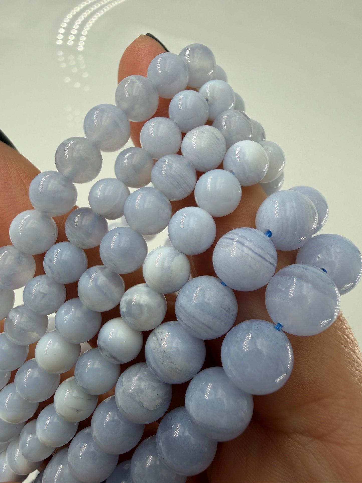 Ein zartblaues Kugelarmband aus poliertem Chalcedon, dessen gleichmäßige Perlen eine sanfte Lichtdurchlässigkeit und einen seidigen Glanz aufweisen.