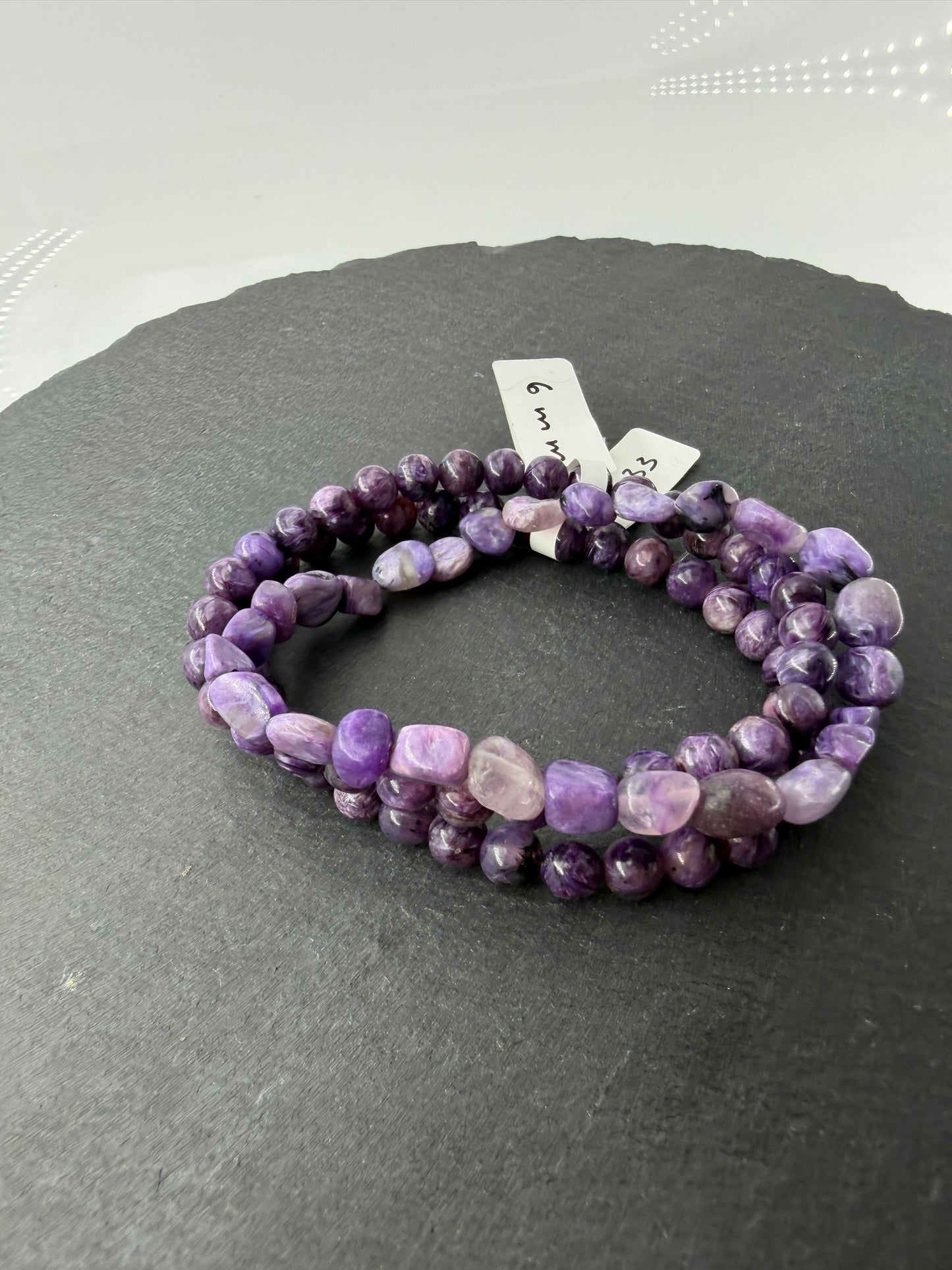 Ein hochwertiges Armband aus tiefvioletten Charoit-Perlen, die eine faszinierende, wirbelförmige Maserung und einen sanften Perlmuttglanz aufweisen.