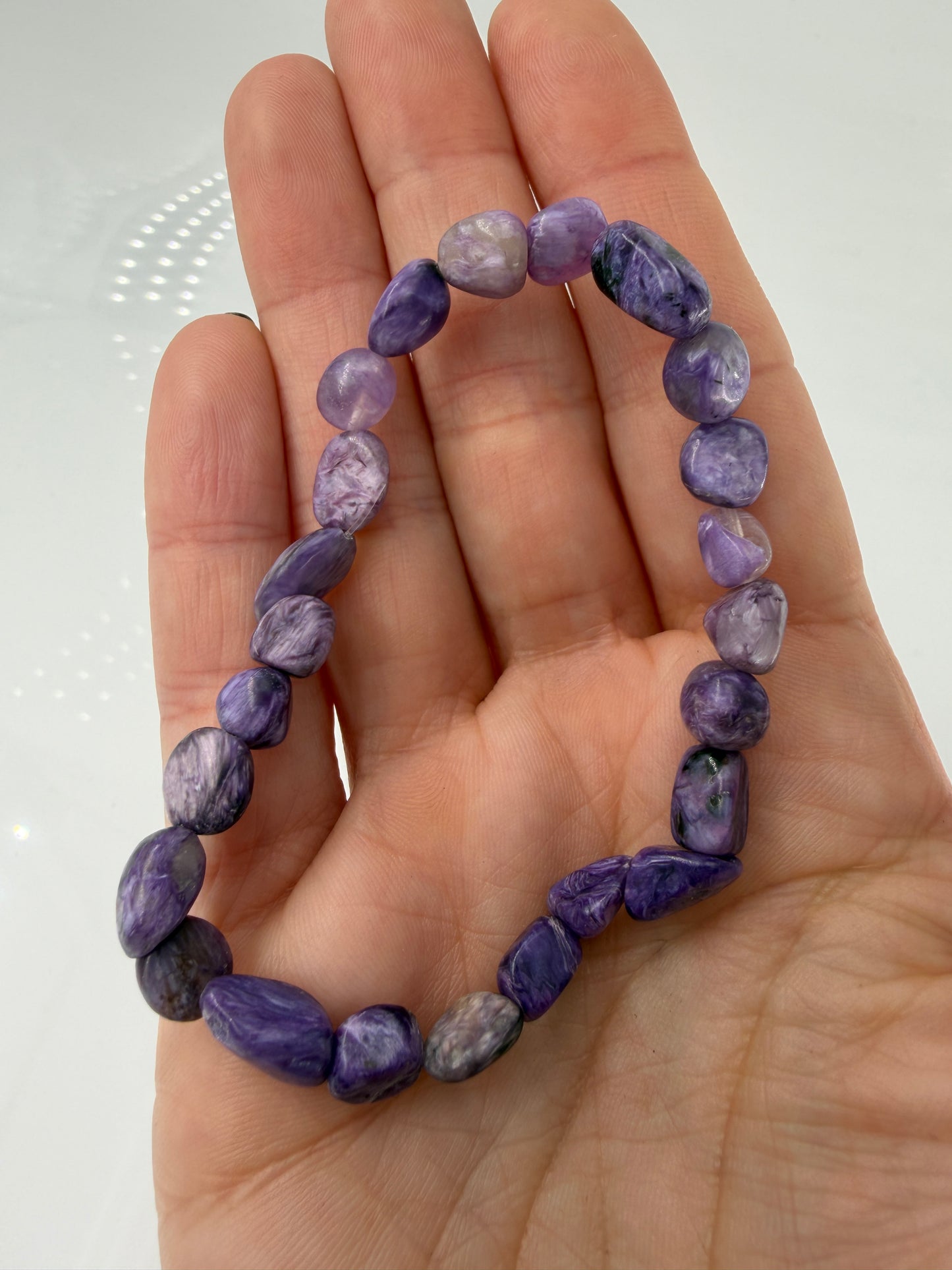 Ein hochwertiges Armband aus tiefvioletten Charoit-Nuggets, die eine faszinierende, wirbelförmige Maserung und einen sanften Perlmuttglanz aufweisen.