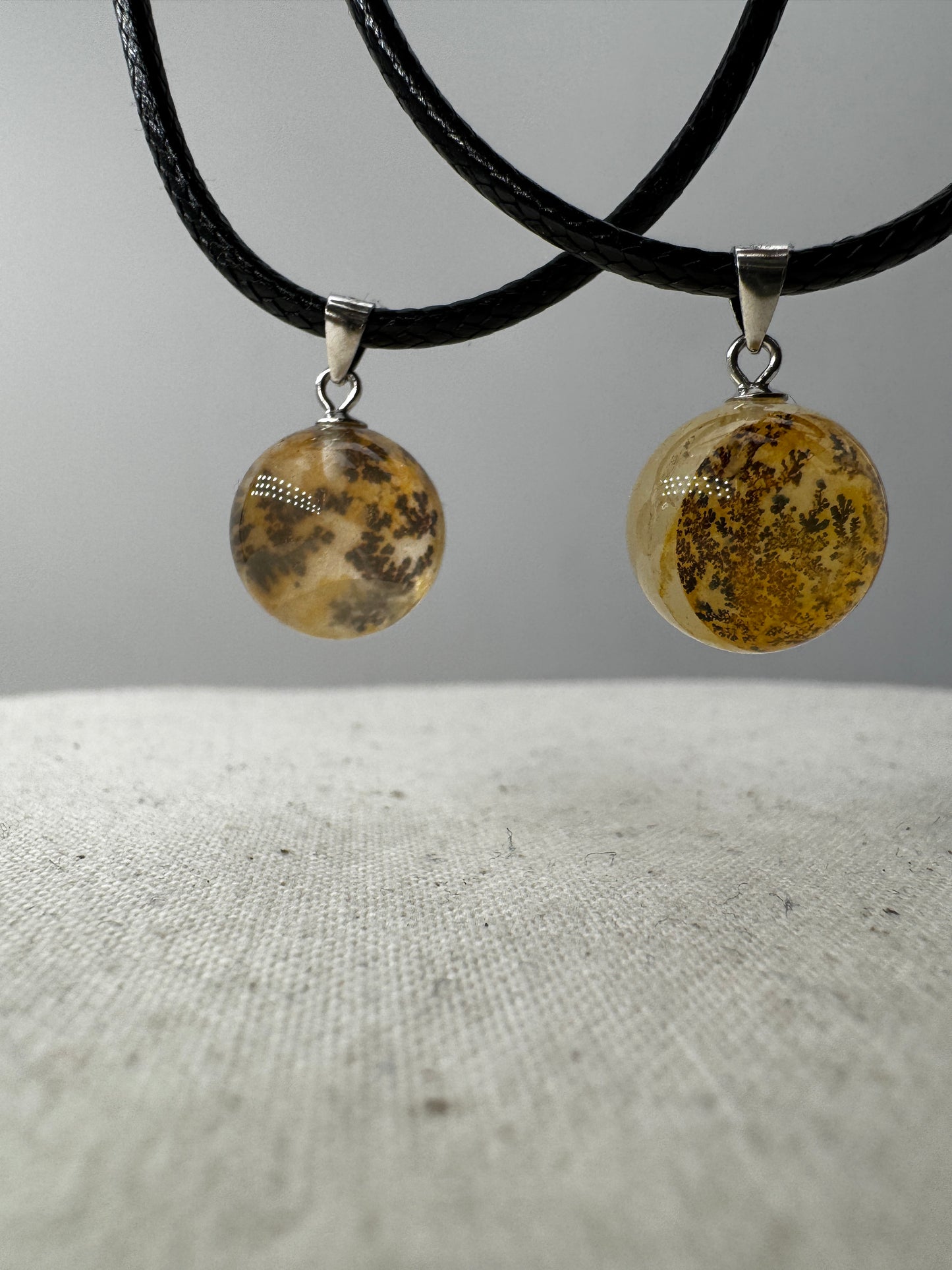 Dendritenquarz-Kugelanhänger mit Mangan-Dendriten und goldenen Eisenoxid-Einschlüssen.