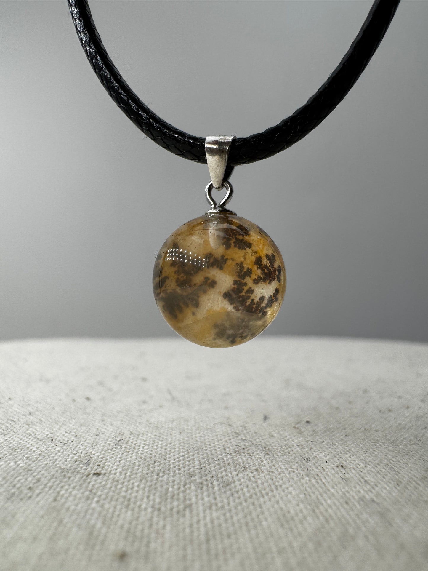 Dendritenquarz-Kugelanhänger mit Mangan-Dendriten und goldenen Eisenoxid-Einschlüssen.