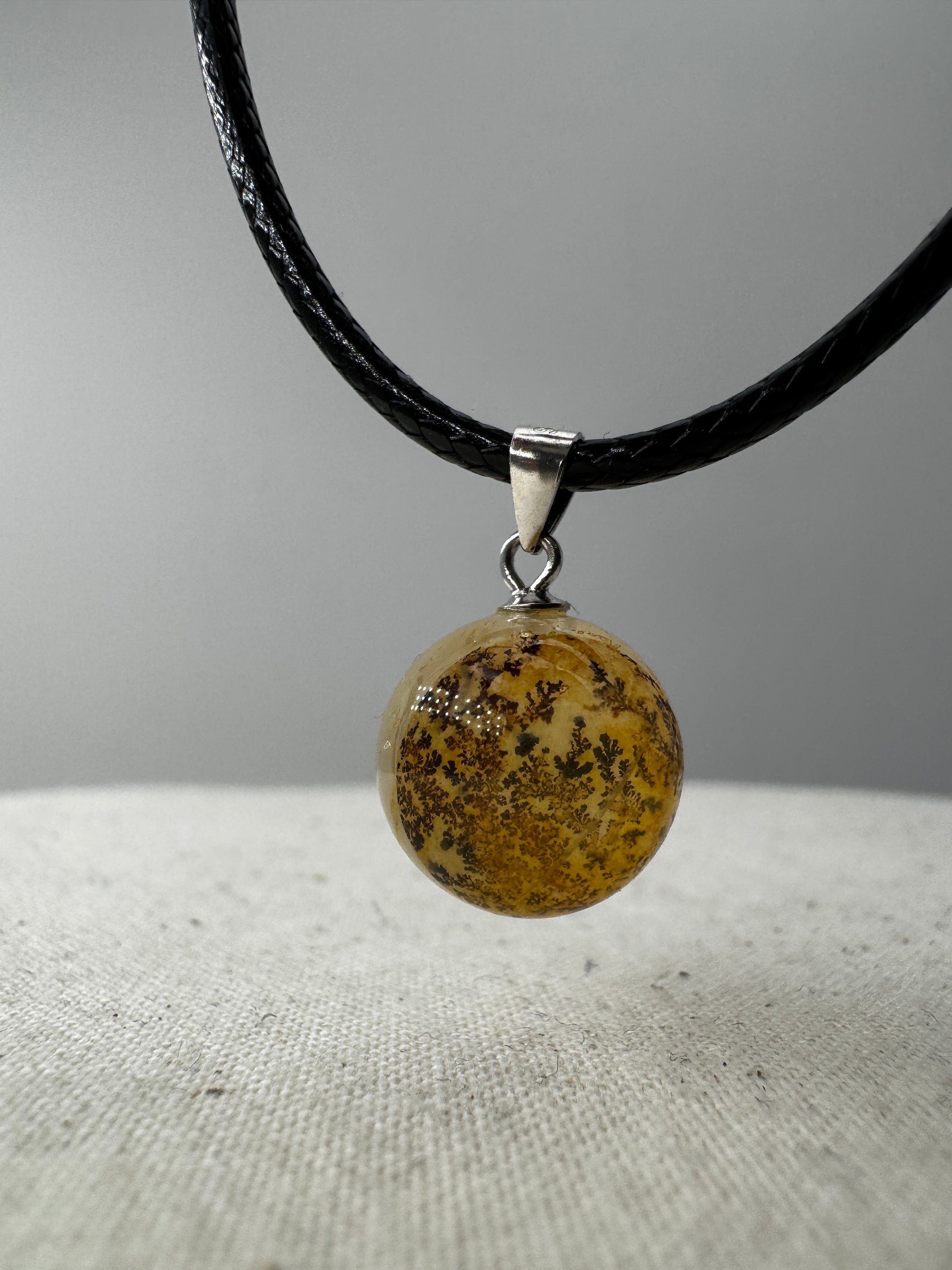 Dendritenquarz-Kugelanhänger mit Mangan-Dendriten und goldenen Eisenoxid-Einschlüssen.