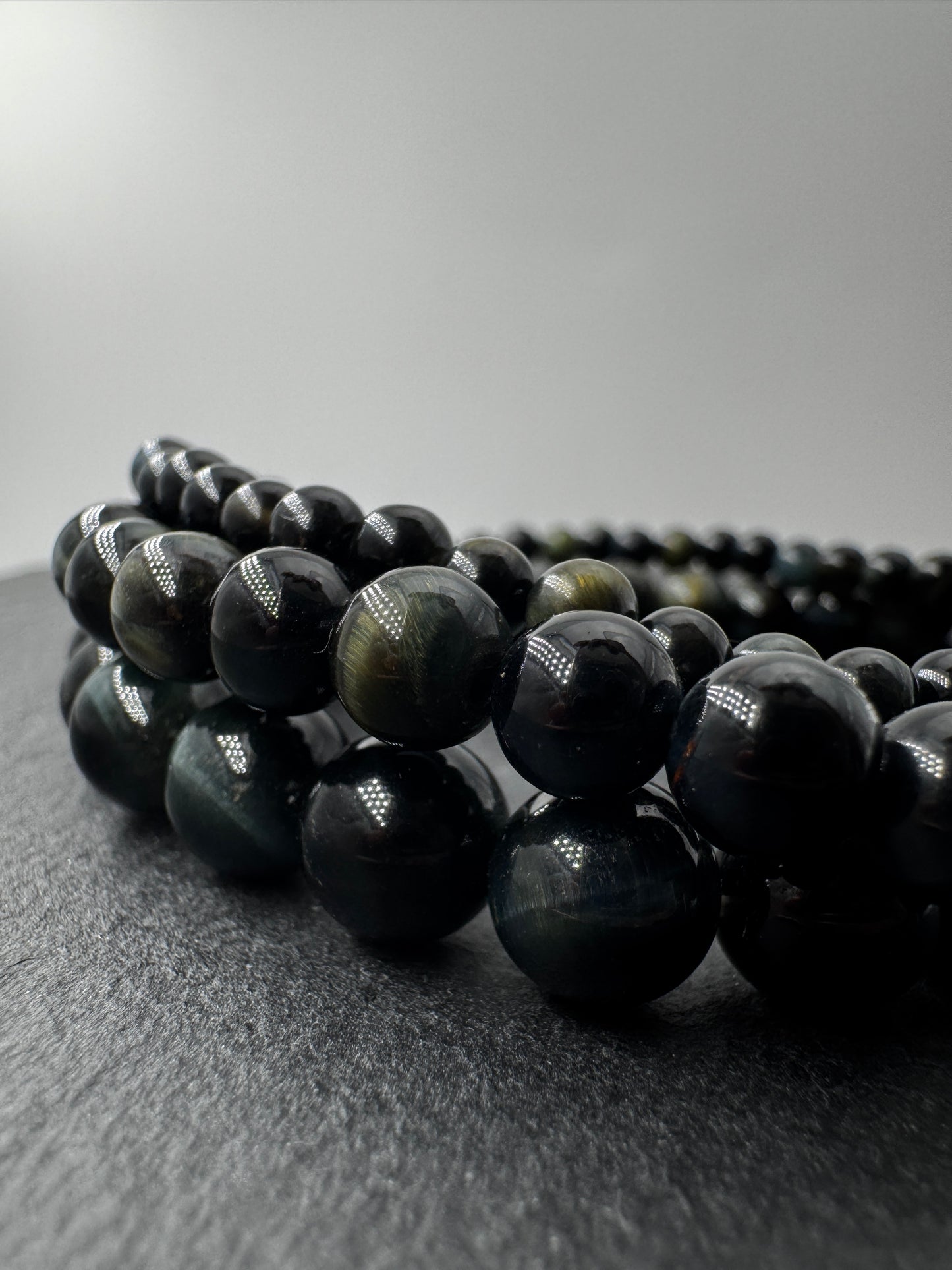 Elegantes Kugelarmband aus dunkelblau-schwarzem Falkenauge mit charakteristischem faserigem Lichtschein.