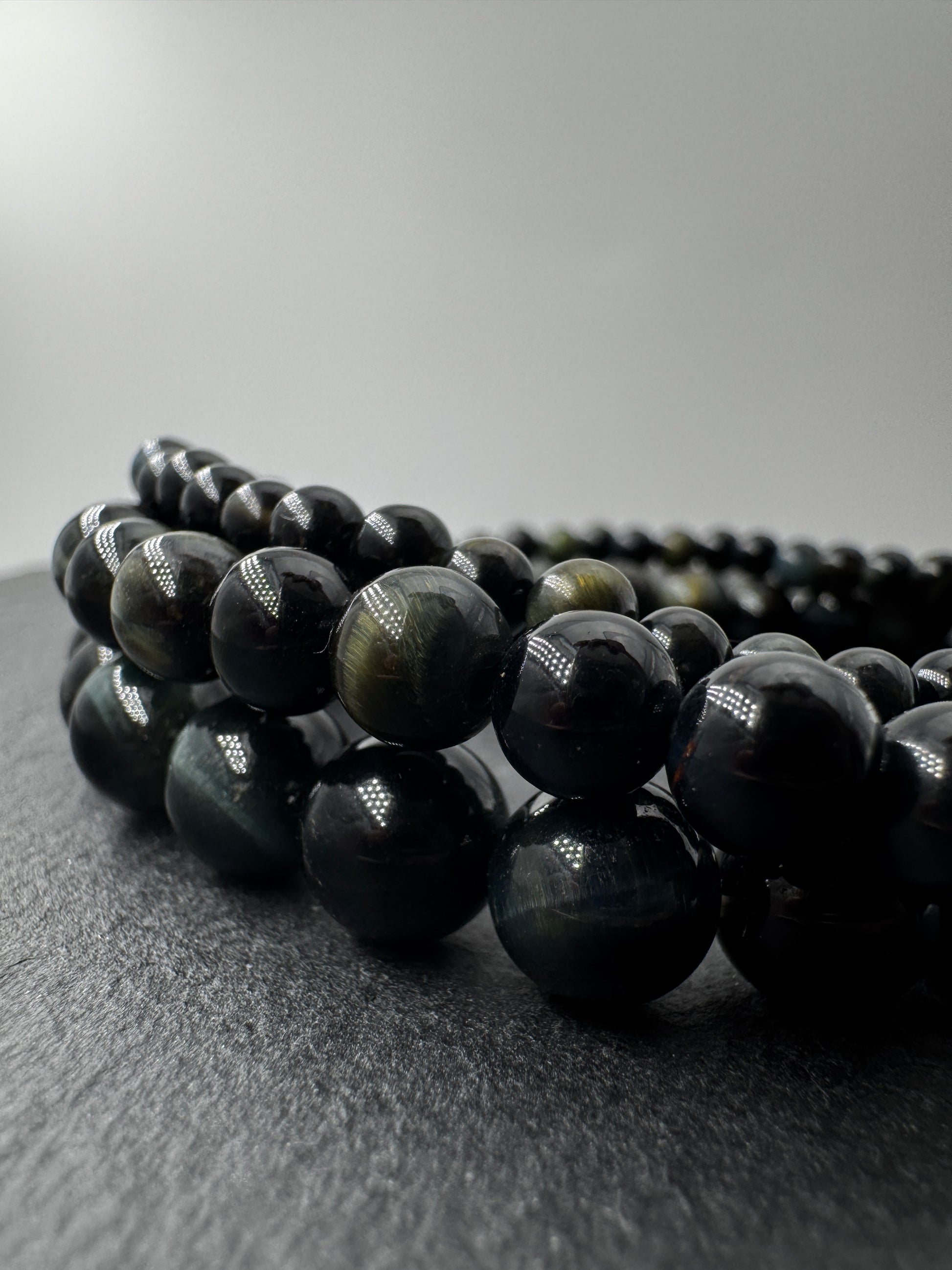 Elegantes Kugelarmband aus dunkelblau-schwarzem Falkenauge mit charakteristischem faserigem Lichtschein.