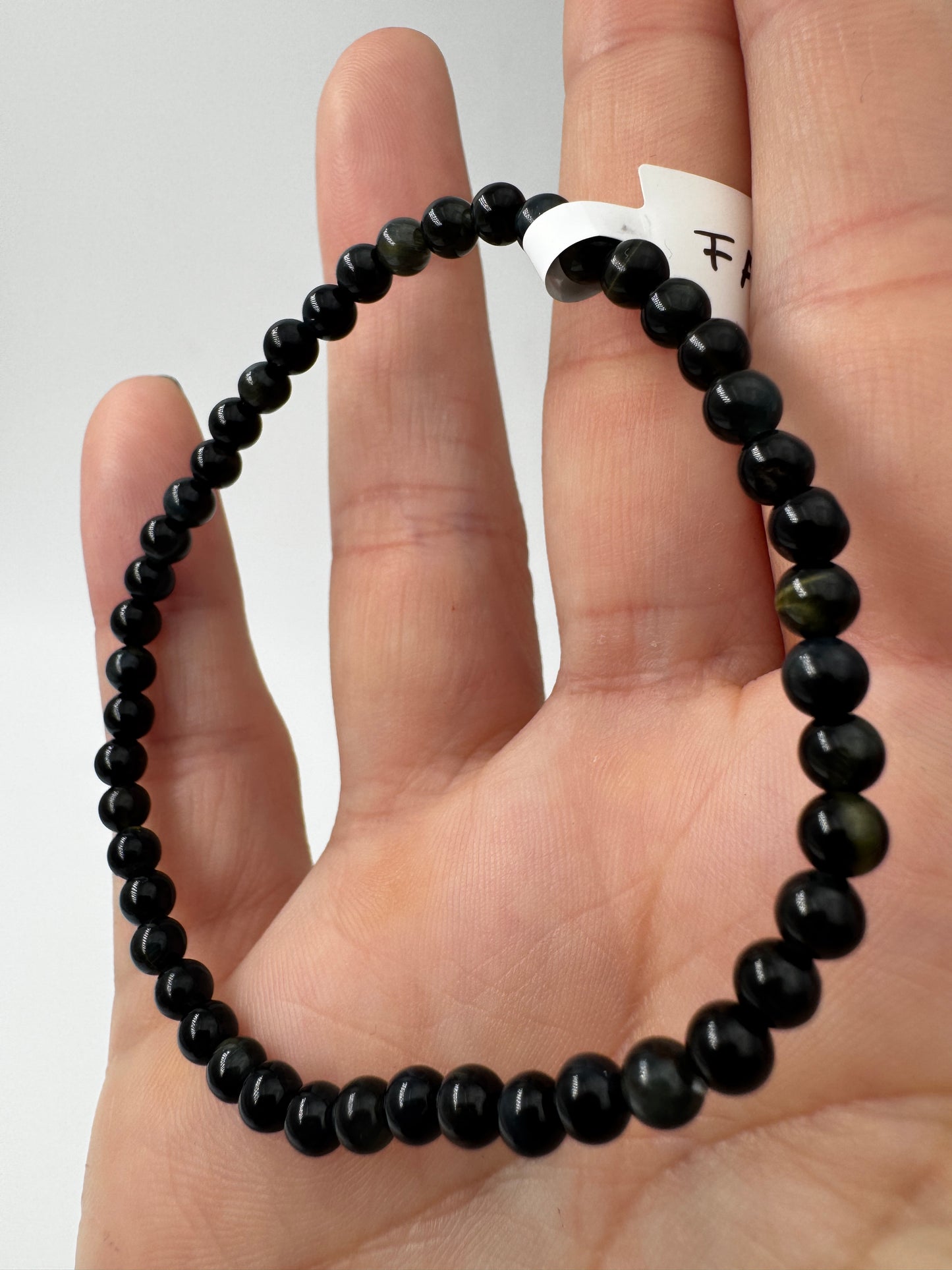 Elegantes Kugelarmband aus dunkelblau-schwarzem Falkenauge mit charakteristischem faserigem Lichtschein.