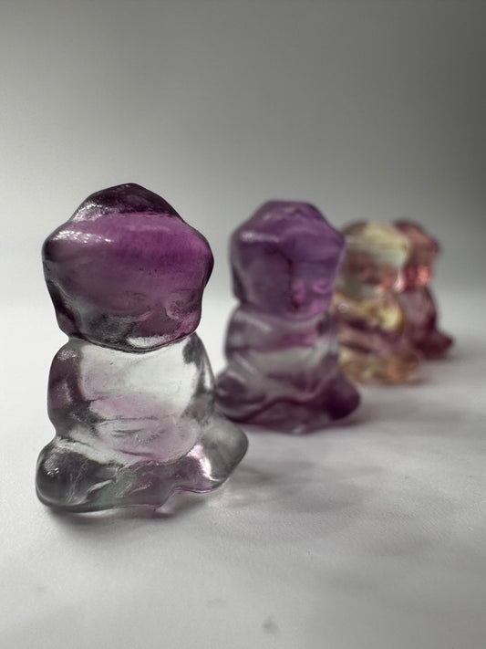 Miniatur-Buddha aus Fluorit FB3 mit glasartigem Glanz, erhältlich in Rosa, Lila, Lila-Blau und Gelb-Lila.