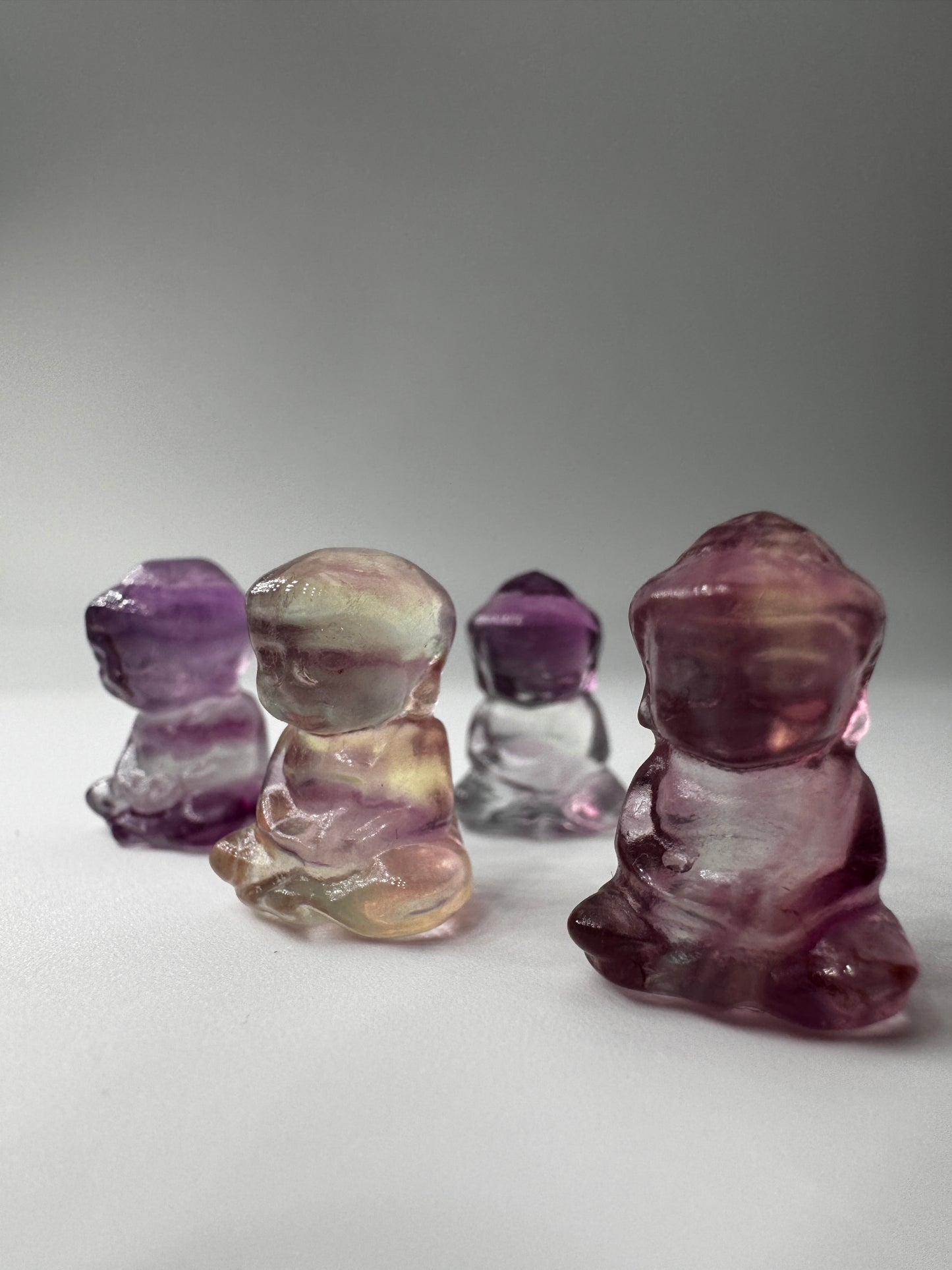 Miniatur-Buddha aus Fluorit FB3 mit glasartigem Glanz, erhältlich in Rosa, Lila, Lila-Blau und Gelb-Lila.