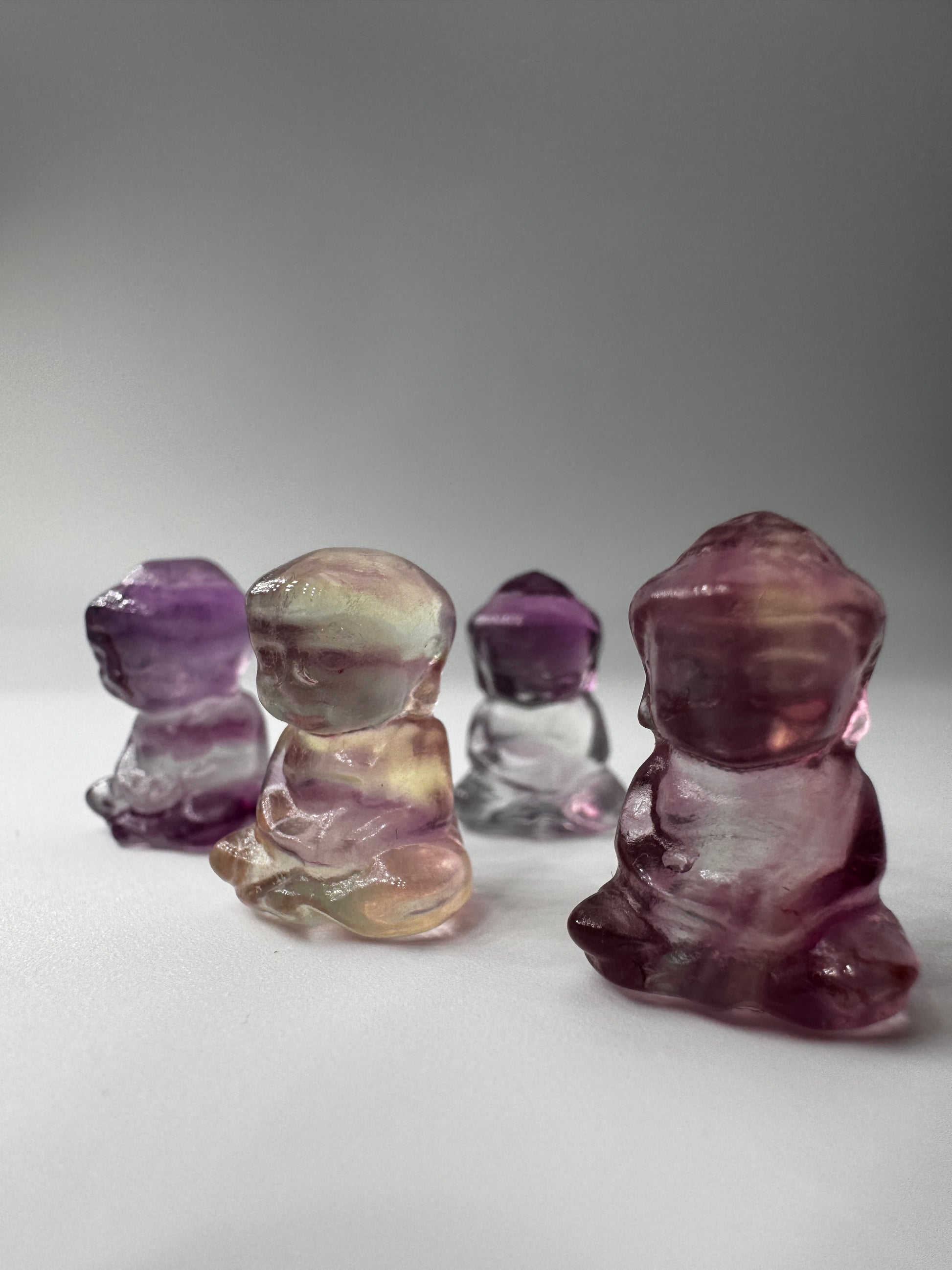 Miniatur-Buddha aus Fluorit FB3 mit glasartigem Glanz, erhältlich in Rosa, Lila, Lila-Blau und Gelb-Lila.