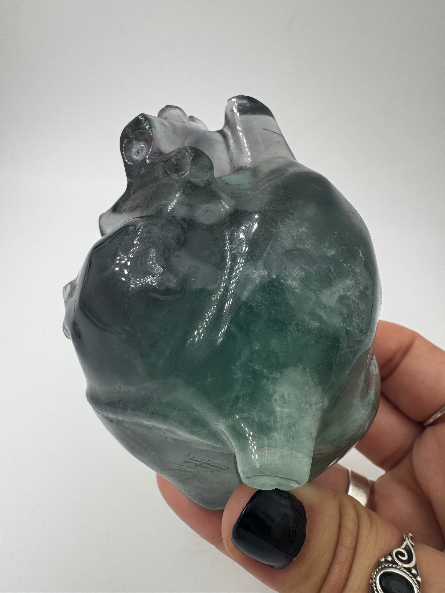 Ein anatomisch geformtes Herz aus Fluorit mit charakteristischen violett-grünen Farbbändern und einer hochglanzpolierten Oberfläche.