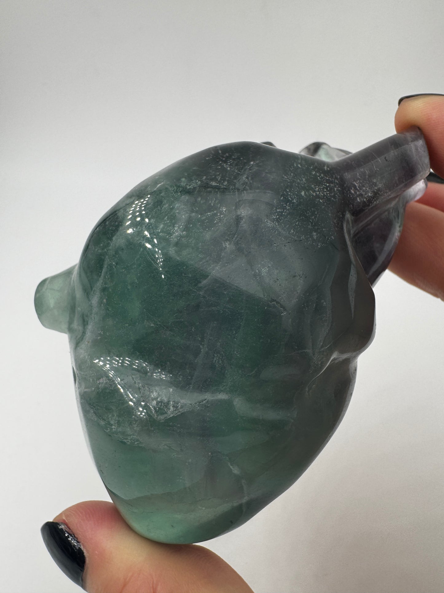 Ein anatomisch geformtes Herz aus Fluorit mit charakteristischen violett-grünen Farbbändern und einer hochglanzpolierten Oberfläche.