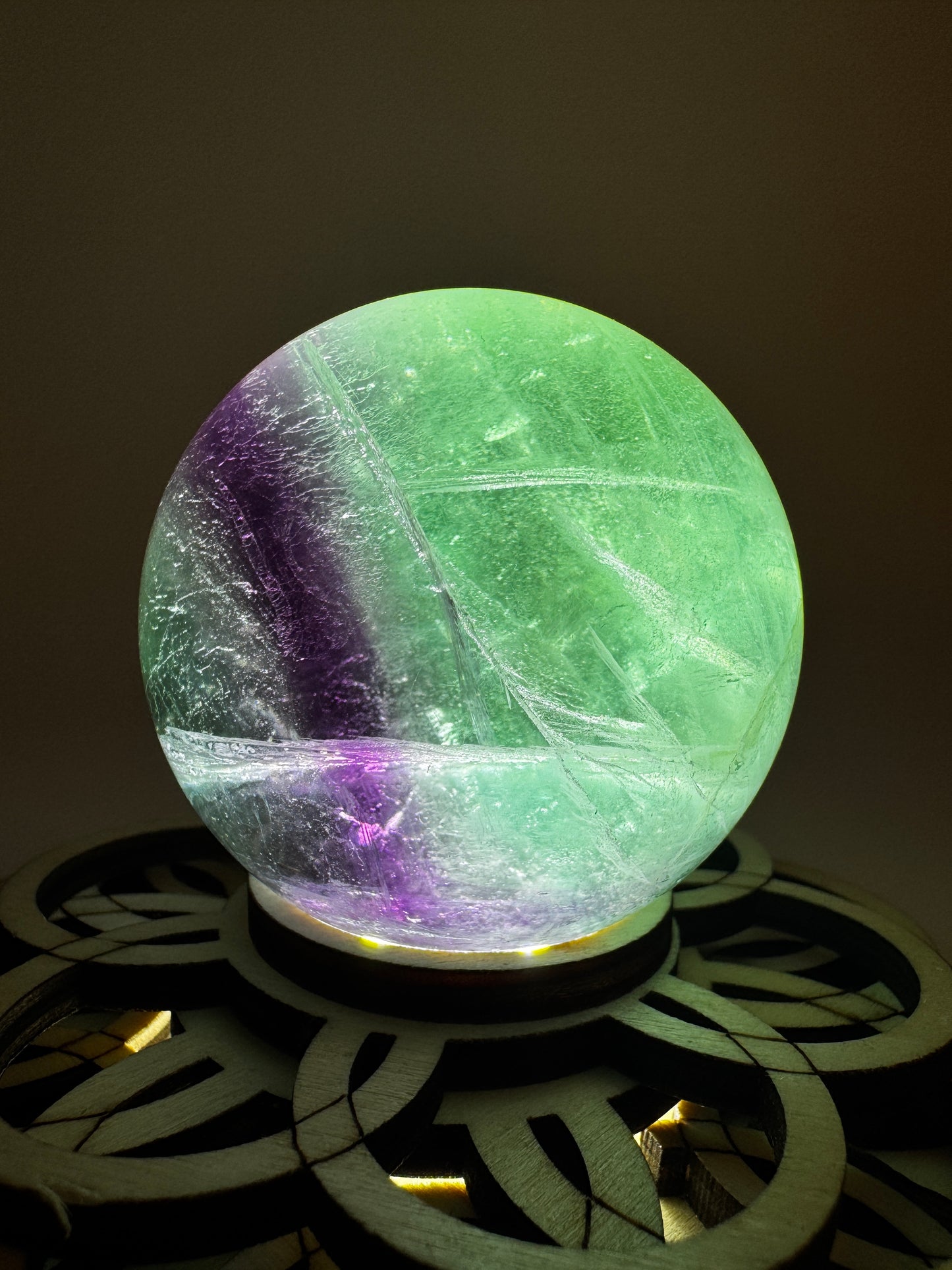 Fluorit-Kugel mit natürlichem Farbverlauf von Smaragdgrün zu Lavendel-Rosa auf einem Leuchtständer.