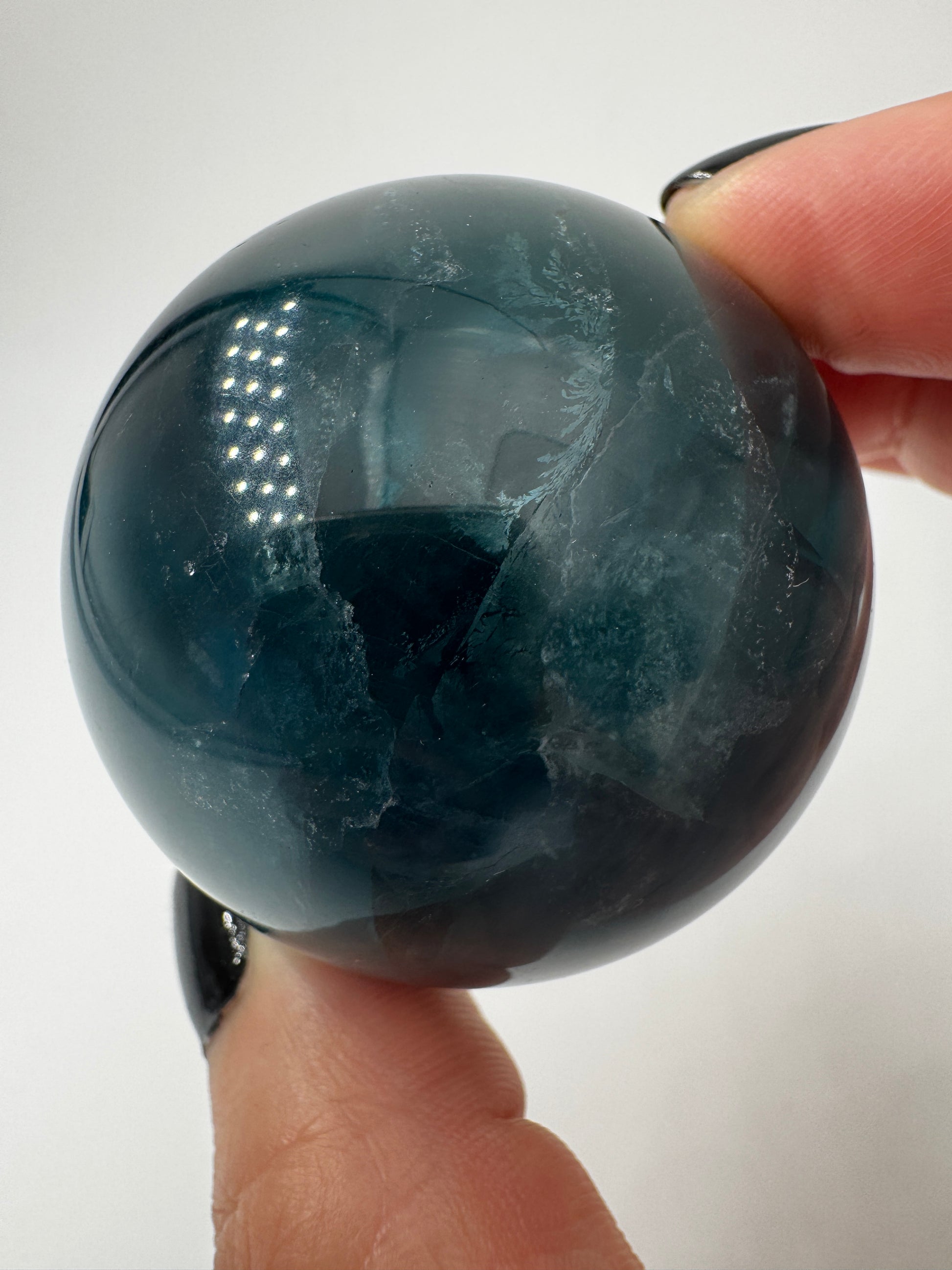 Eine perfekt polierte Kugel aus blauem Fluorit mit faszinierenden Farbzonen.