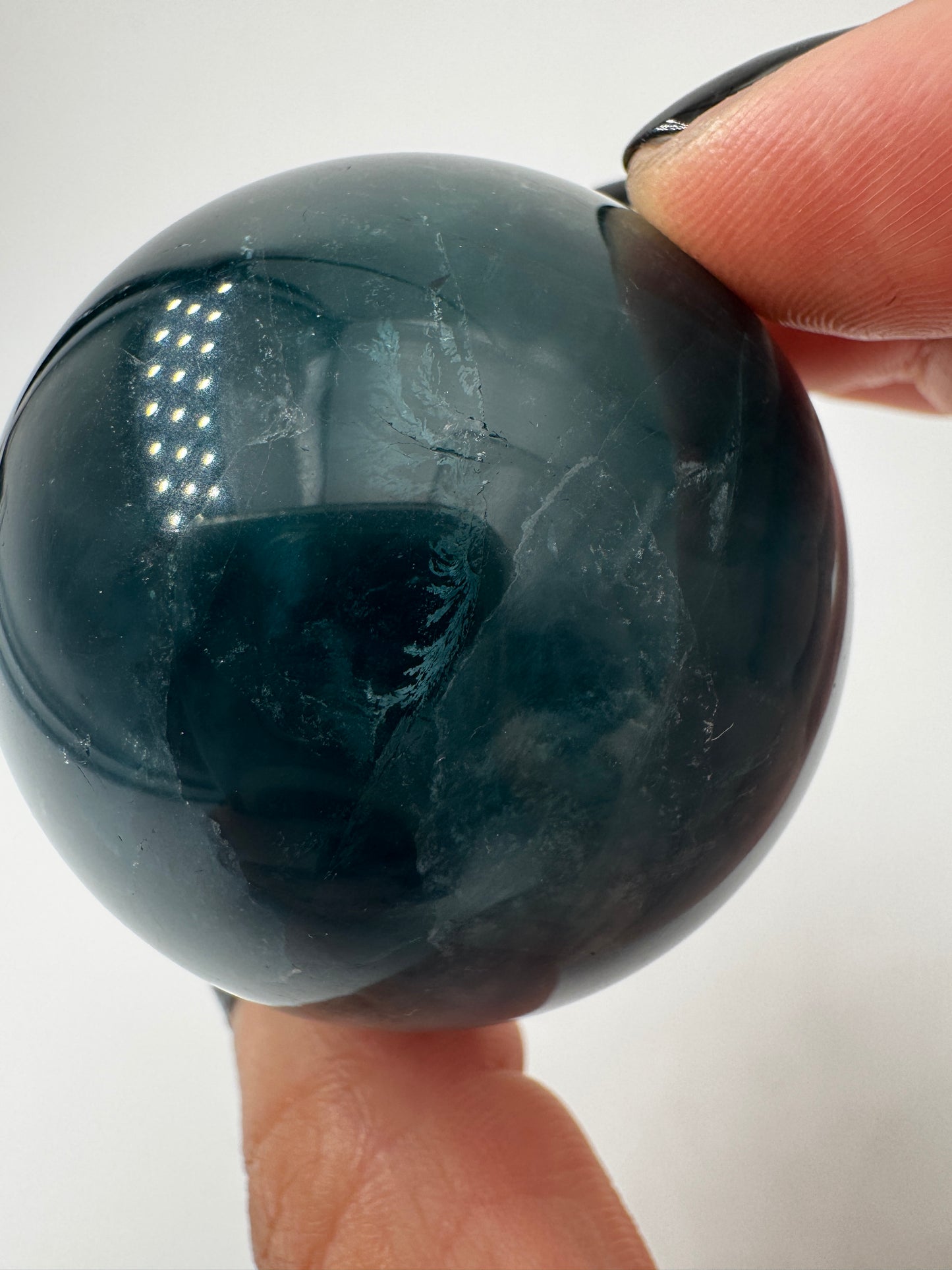 Eine perfekt polierte Kugel aus blauem Fluorit mit faszinierenden Farbzonen.