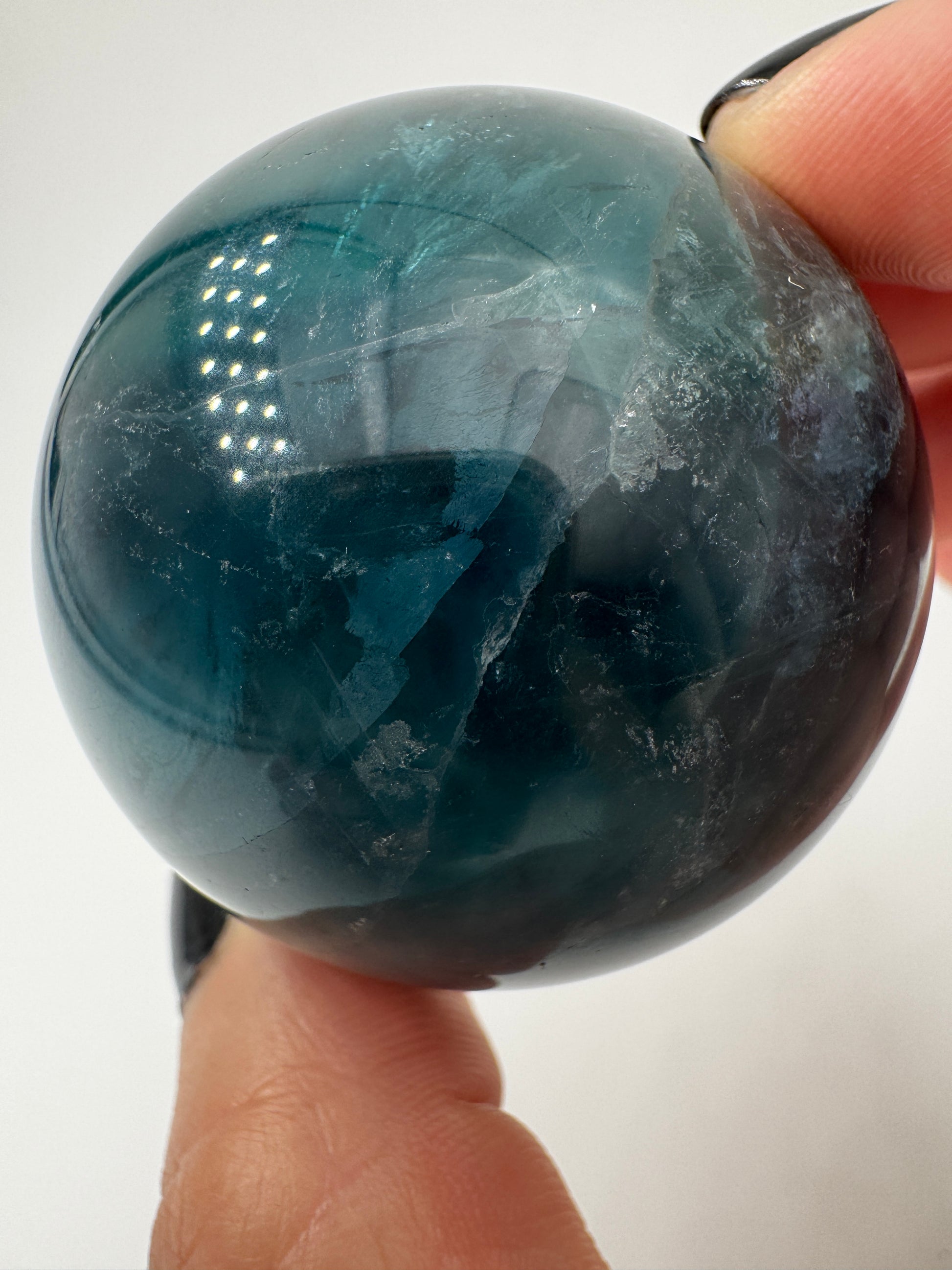 Eine perfekt polierte Kugel aus blauem Fluorit mit faszinierenden Farbzonen.