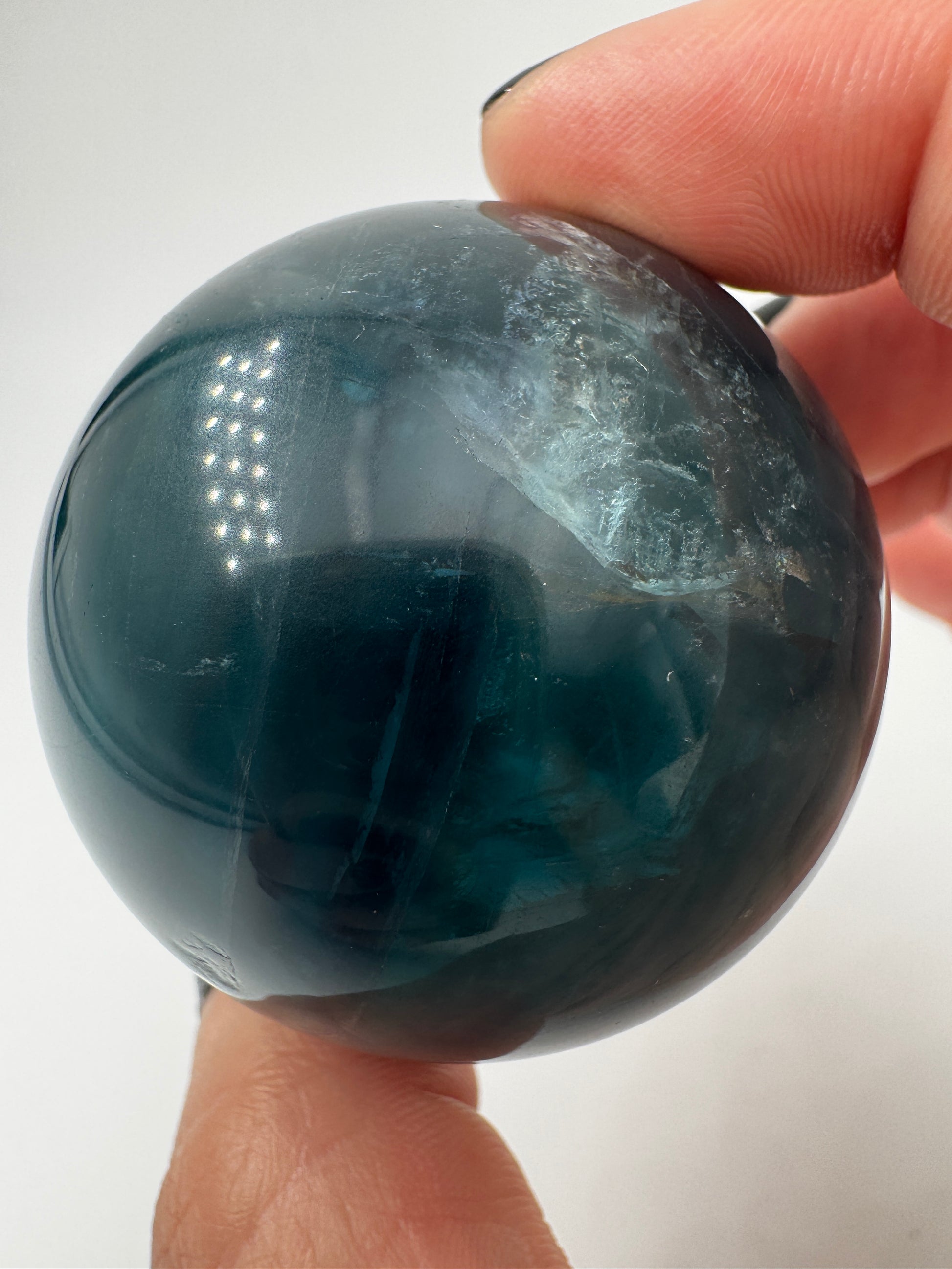 Eine perfekt polierte Kugel aus blauem Fluorit mit faszinierenden Farbzonen.