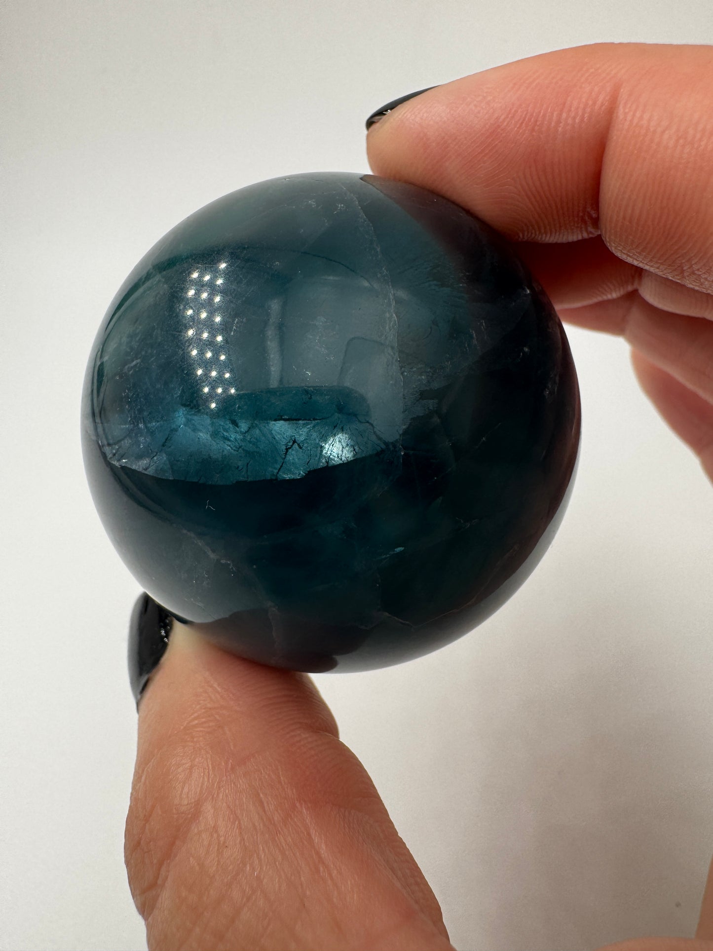Eine perfekt polierte Kugel aus blauem Fluorit mit faszinierenden Farbzonen.