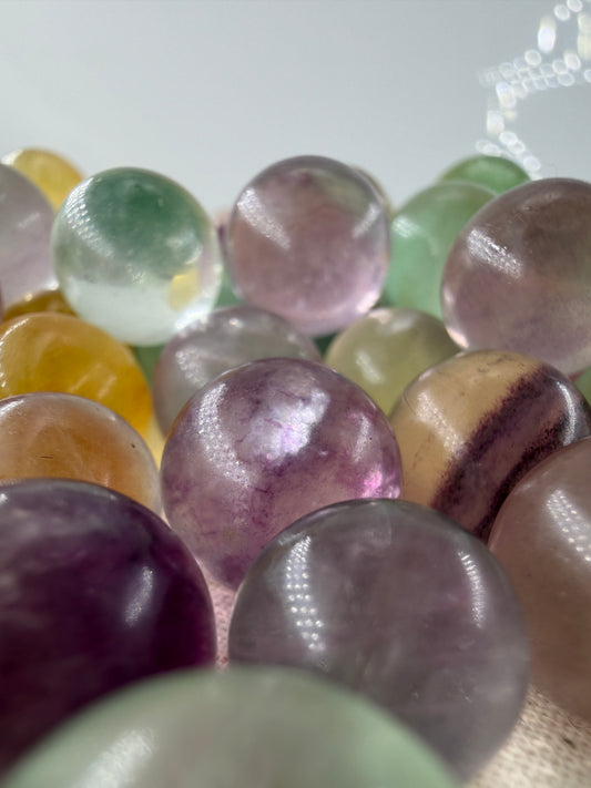 Fluorit Minikugel mit zonarer Farbgebung in Violett und Grün und Gelb.