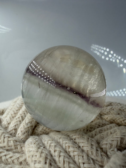 Polierte weiße Fluorit-Kugel mit deutlich erkennbaren, goldfarben glänzenden Pyrit-Kristallen.