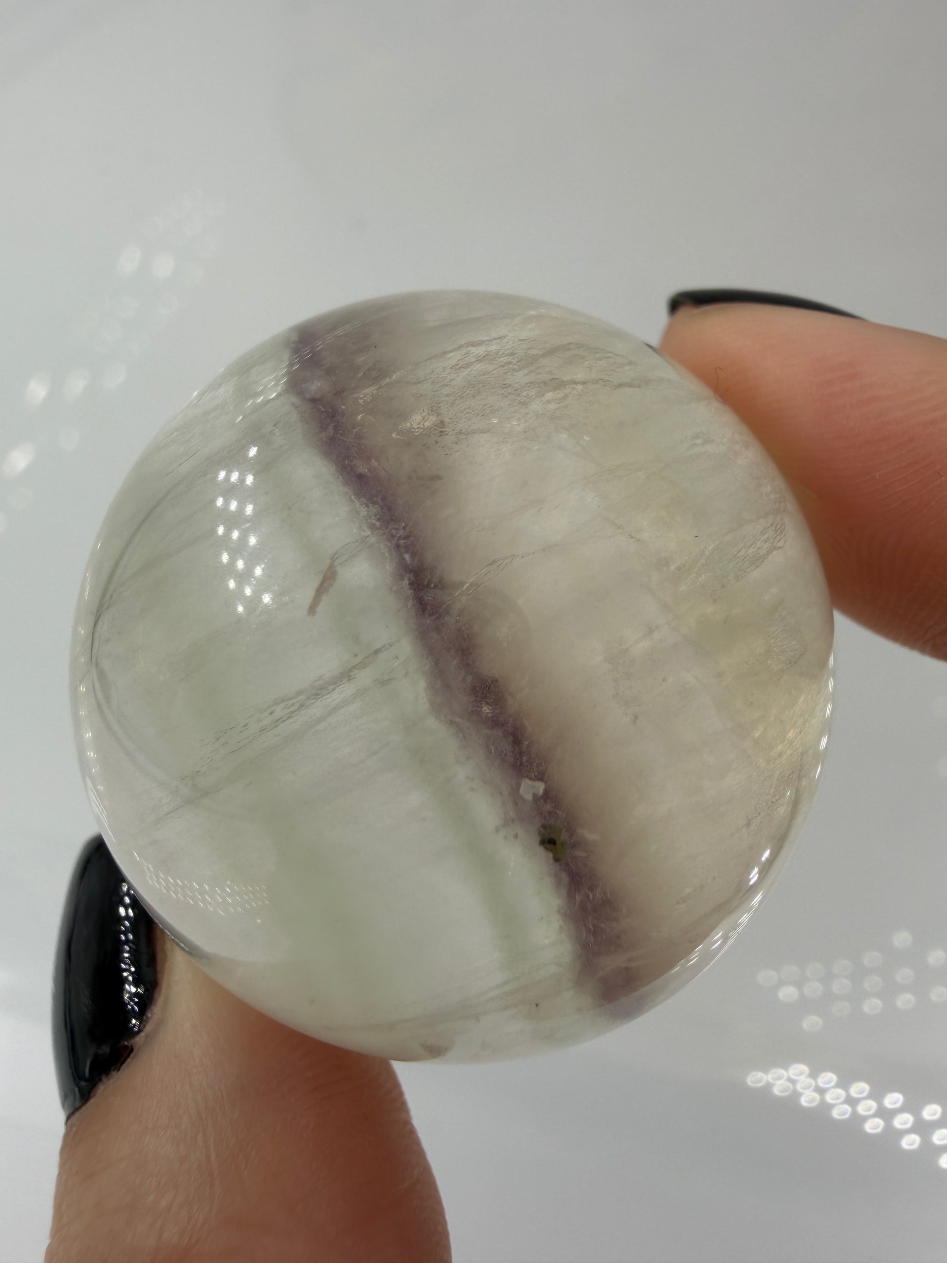 Polierte weiße Fluorit-Kugel mit deutlich erkennbaren, goldfarben glänzenden Pyrit-Kristallen.