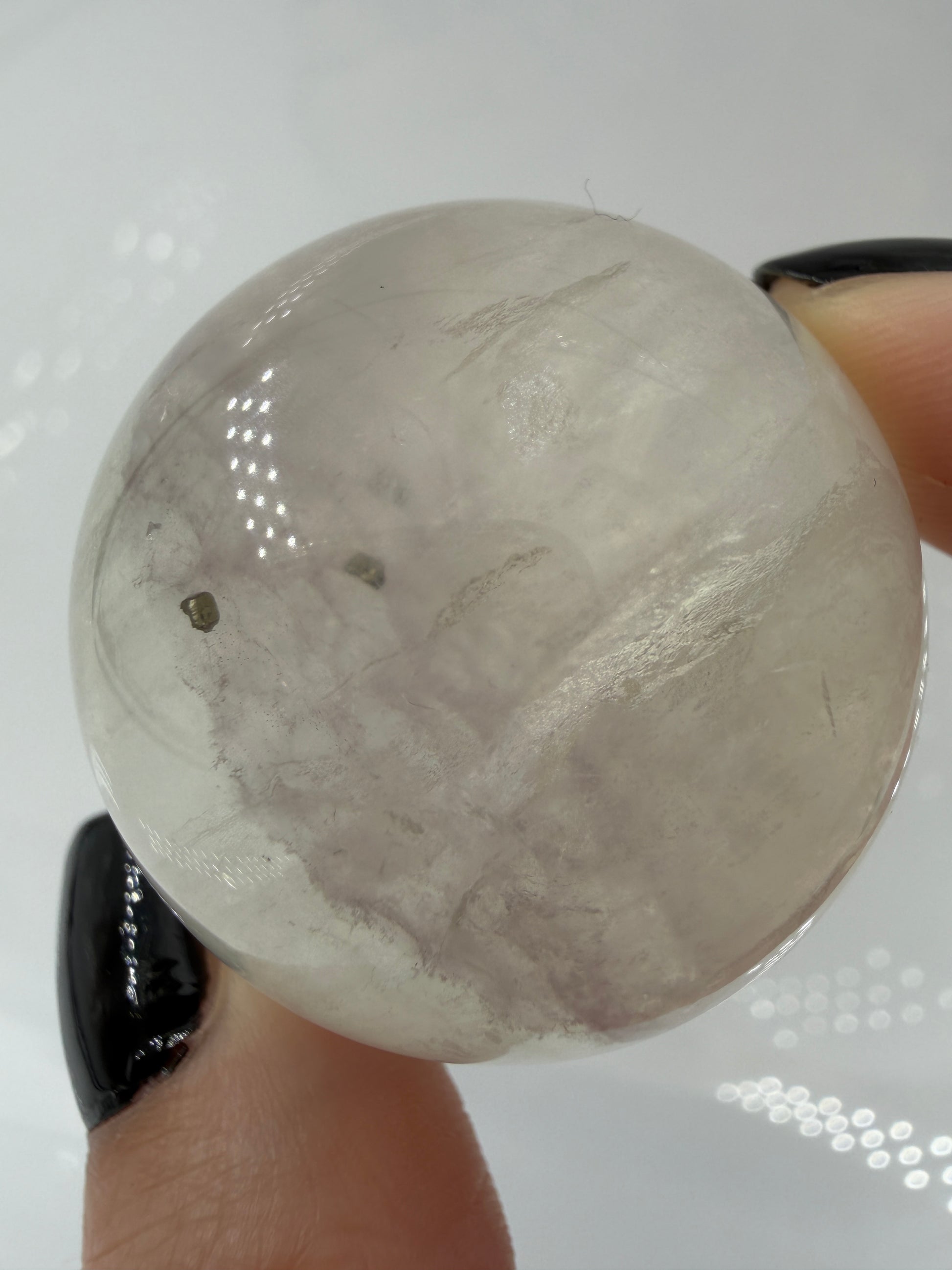 Polierte weiße Fluorit-Kugel mit deutlich erkennbaren, goldfarben glänzenden Pyrit-Kristallen.