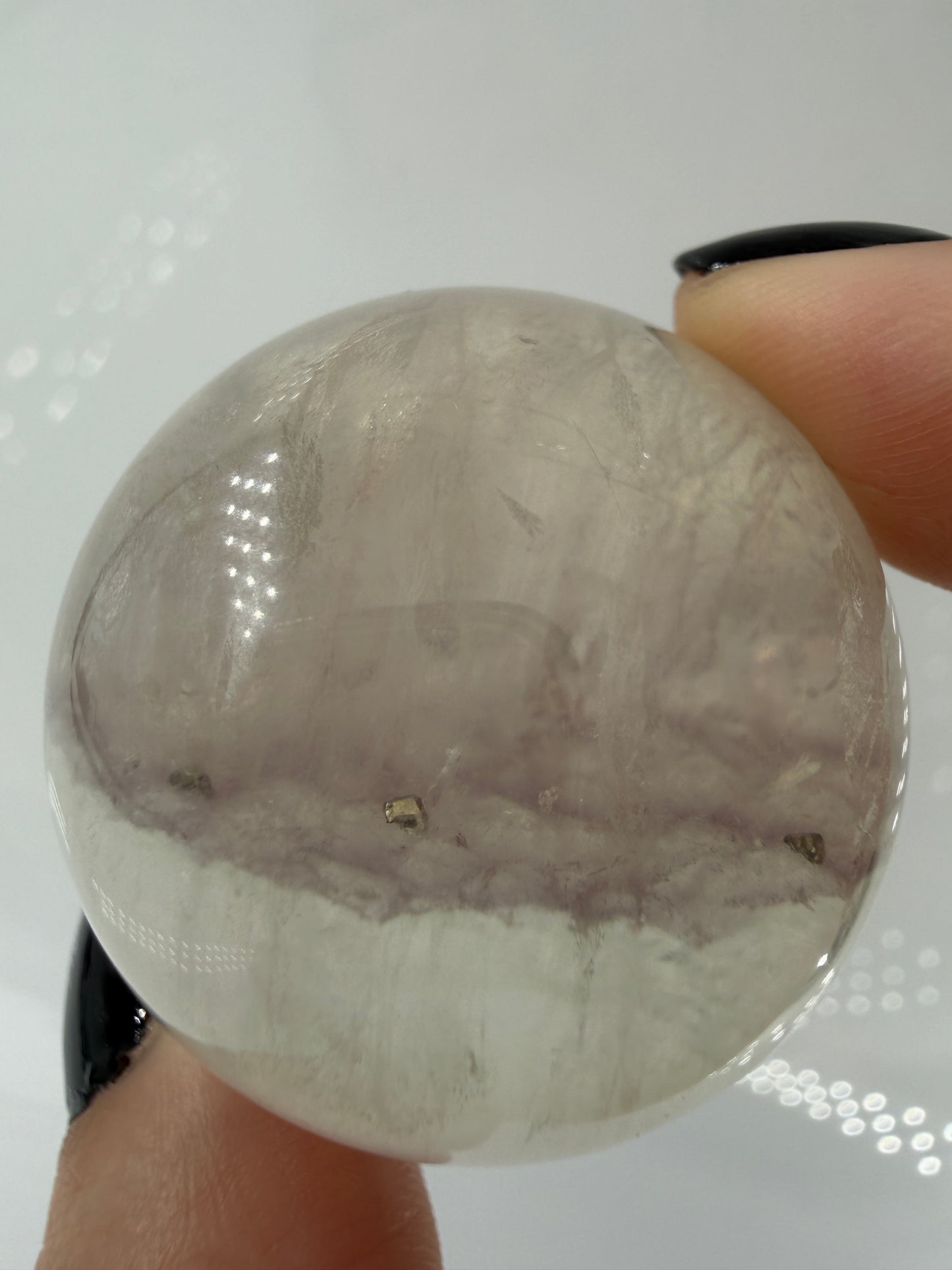 Polierte weiße Fluorit-Kugel mit deutlich erkennbaren, goldfarben glänzenden Pyrit-Kristallen.